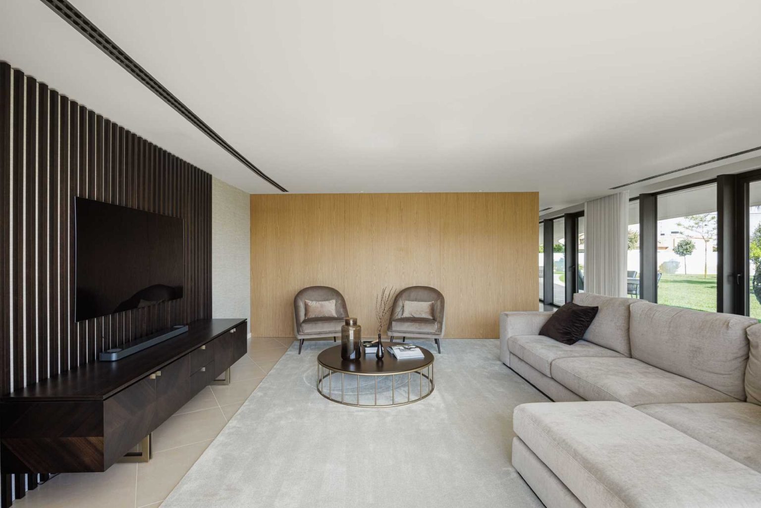 Warm wood cabinetry, polished concrete floors, and a flowing curved wall create a modern open-plan living space full of texture and natural light.
