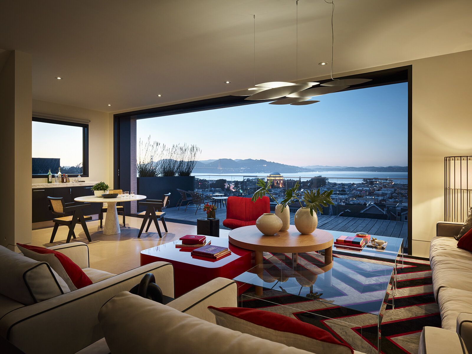 Floor-to-ceiling glass, water views, and bold accents make this contemporary living room feel bright from morning to night. See how layered textures and sculptural lighting create a space that's equally suited to relaxing and entertaining.