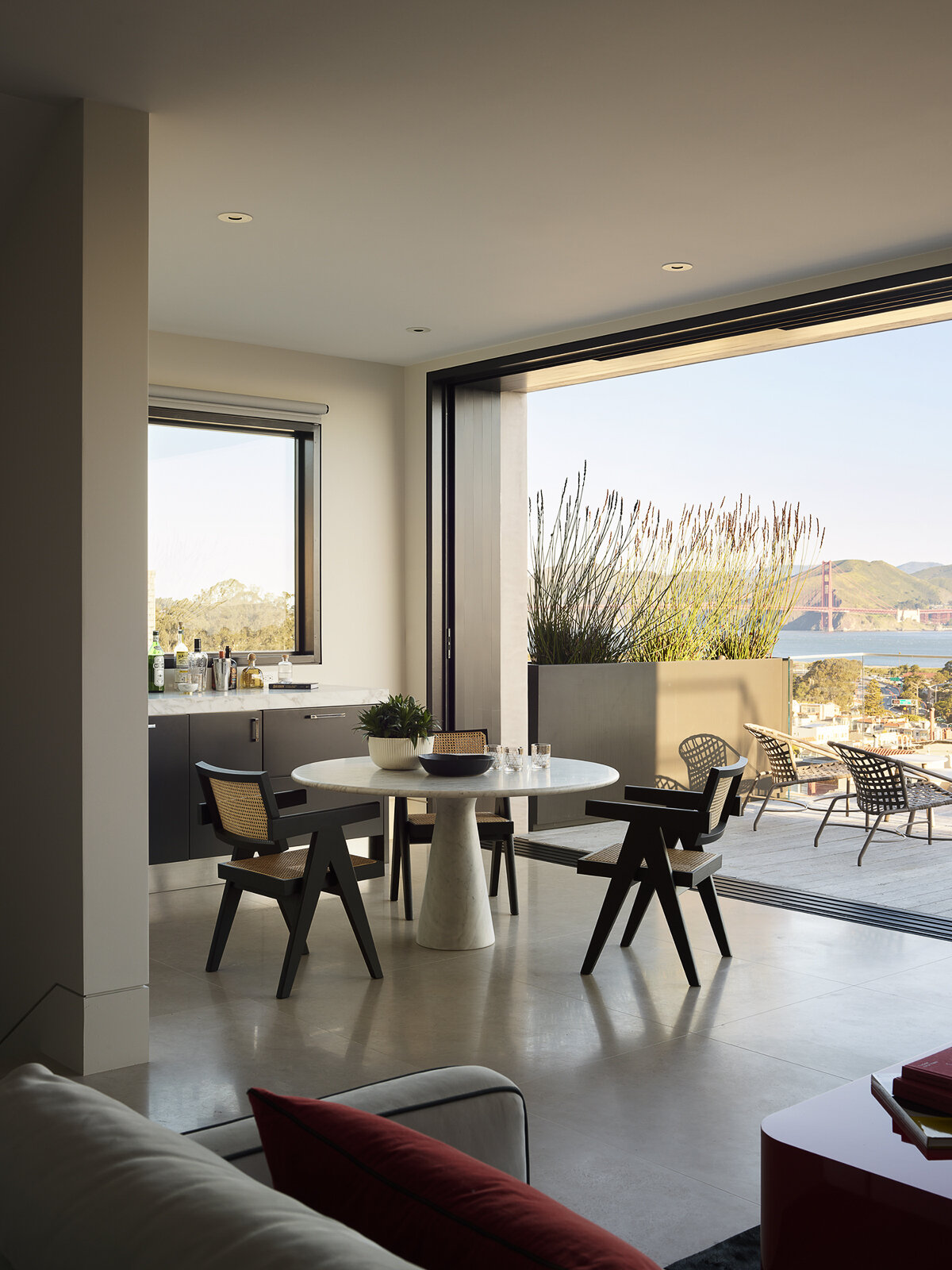 Floor-to-ceiling glass, water views, and bold accents make this contemporary living room feel bright from morning to night. See how layered textures and sculptural lighting create a space that's equally suited to relaxing and entertaining.