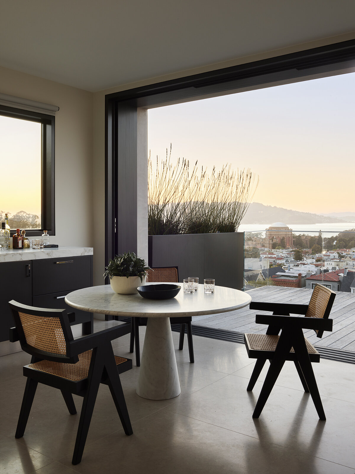 Floor-to-ceiling glass, water views, and bold accents make this contemporary living room feel bright from morning to night. See how layered textures and sculptural lighting create a space that's equally suited to relaxing and entertaining.