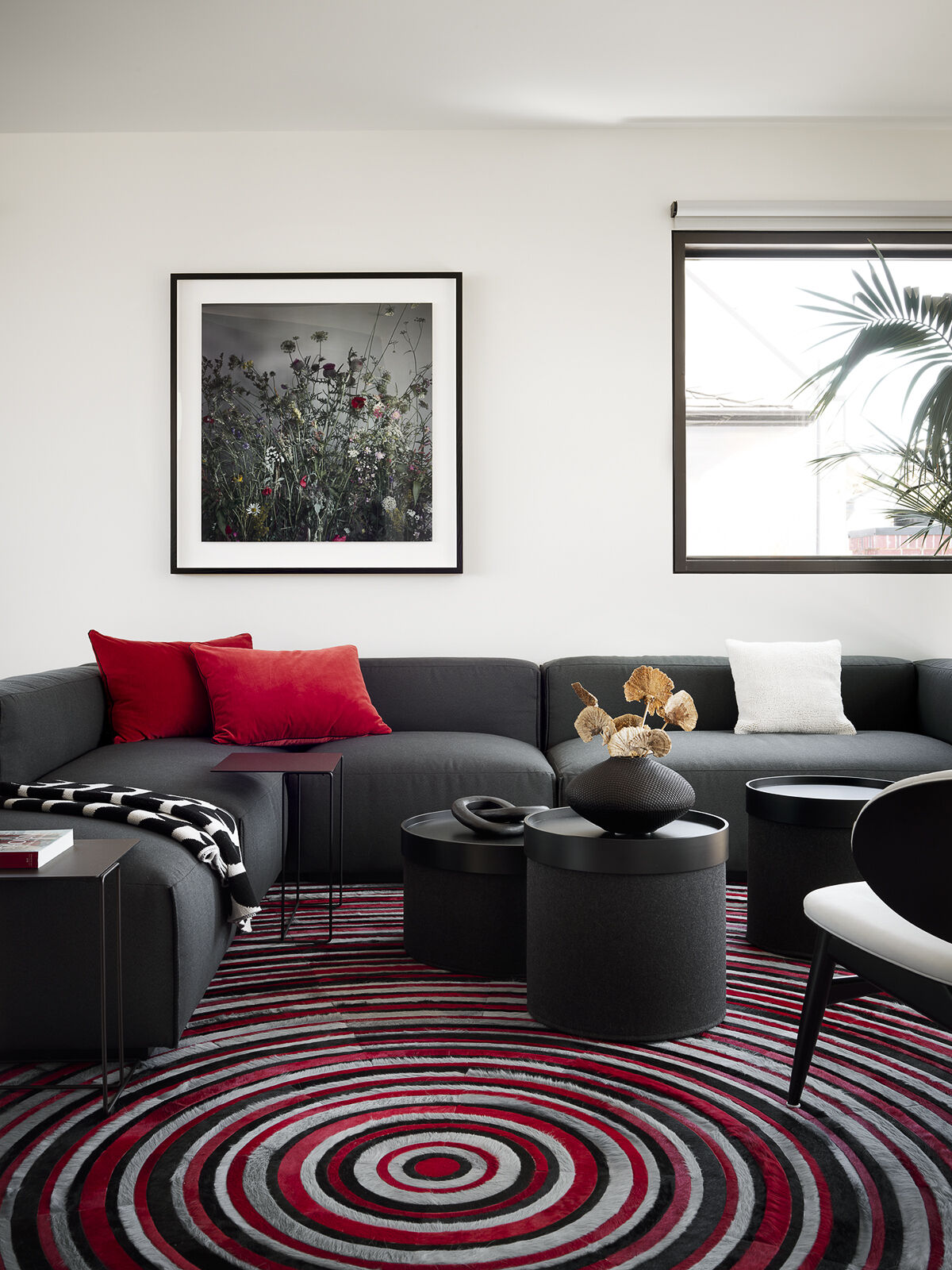 A charcoal sectional, graphic rug, and warm red accents give this cozy living room plenty of personality. Explore how bold colors and tactile finishes create an inviting space for everyday living.