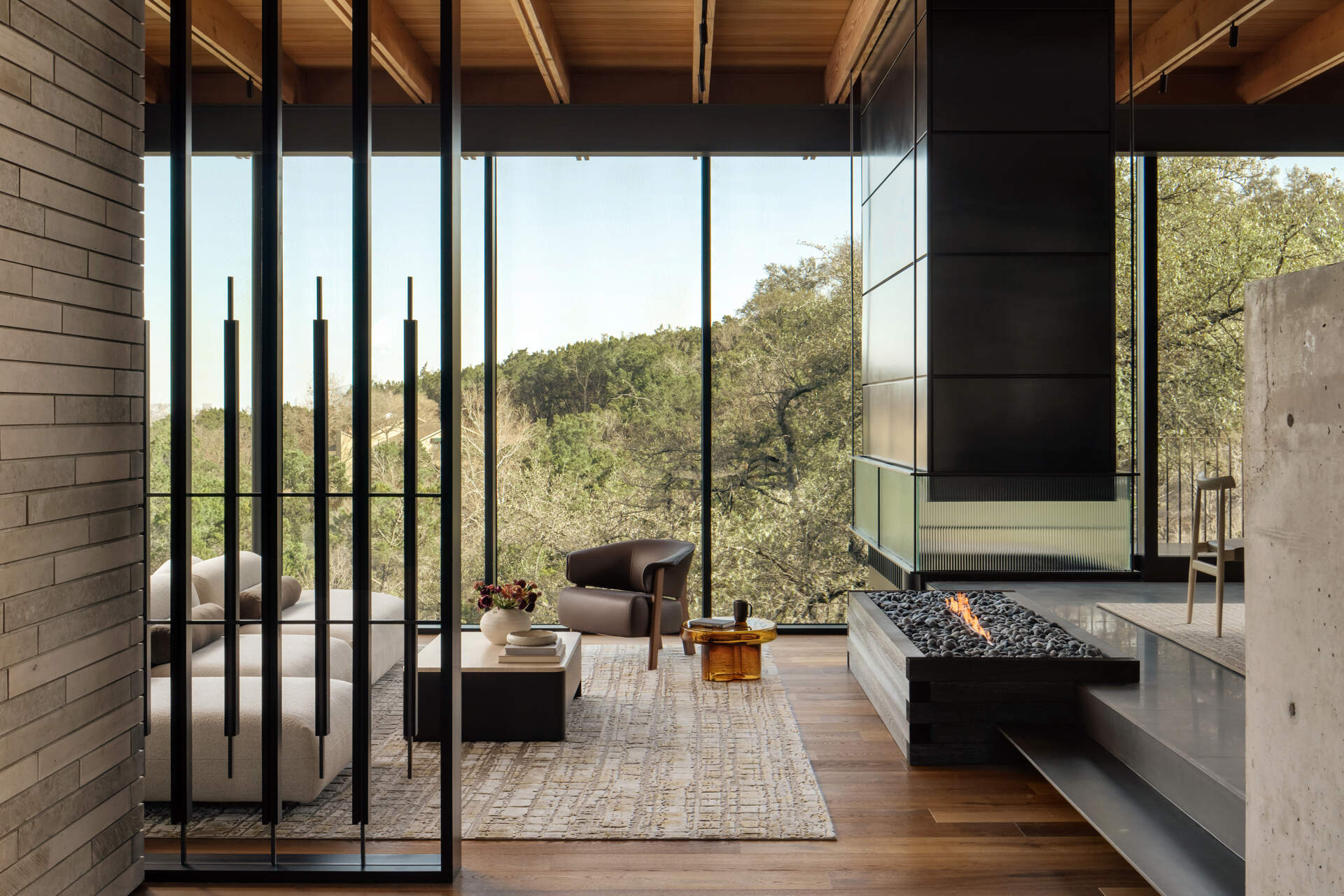 Floor-to-ceiling glass, panoramic views and a sculptural hearth define this beautiful Texas living room.
