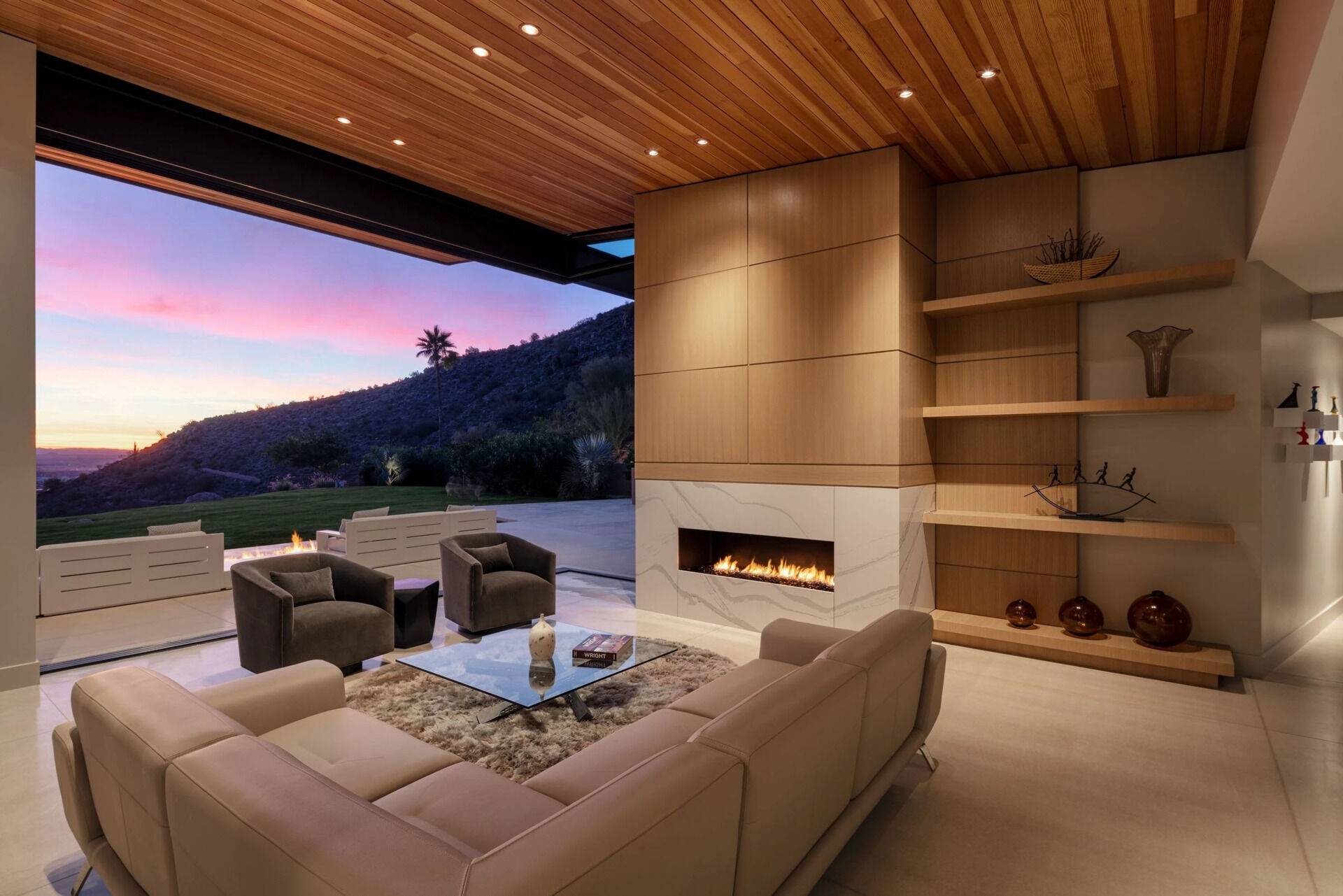 Explore a cozy second lounge with a fireplace and sliding glass walls that open directly onto the landscape.