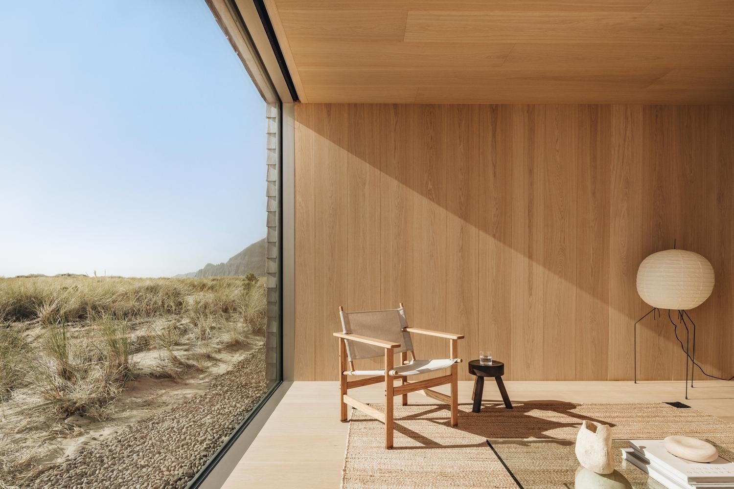 One of the home's defining features is the way it captures the surrounding landscape. Large horizontal openings stretch across bedrooms and living spaces, turning the rolling coastal dunes into living artwork.