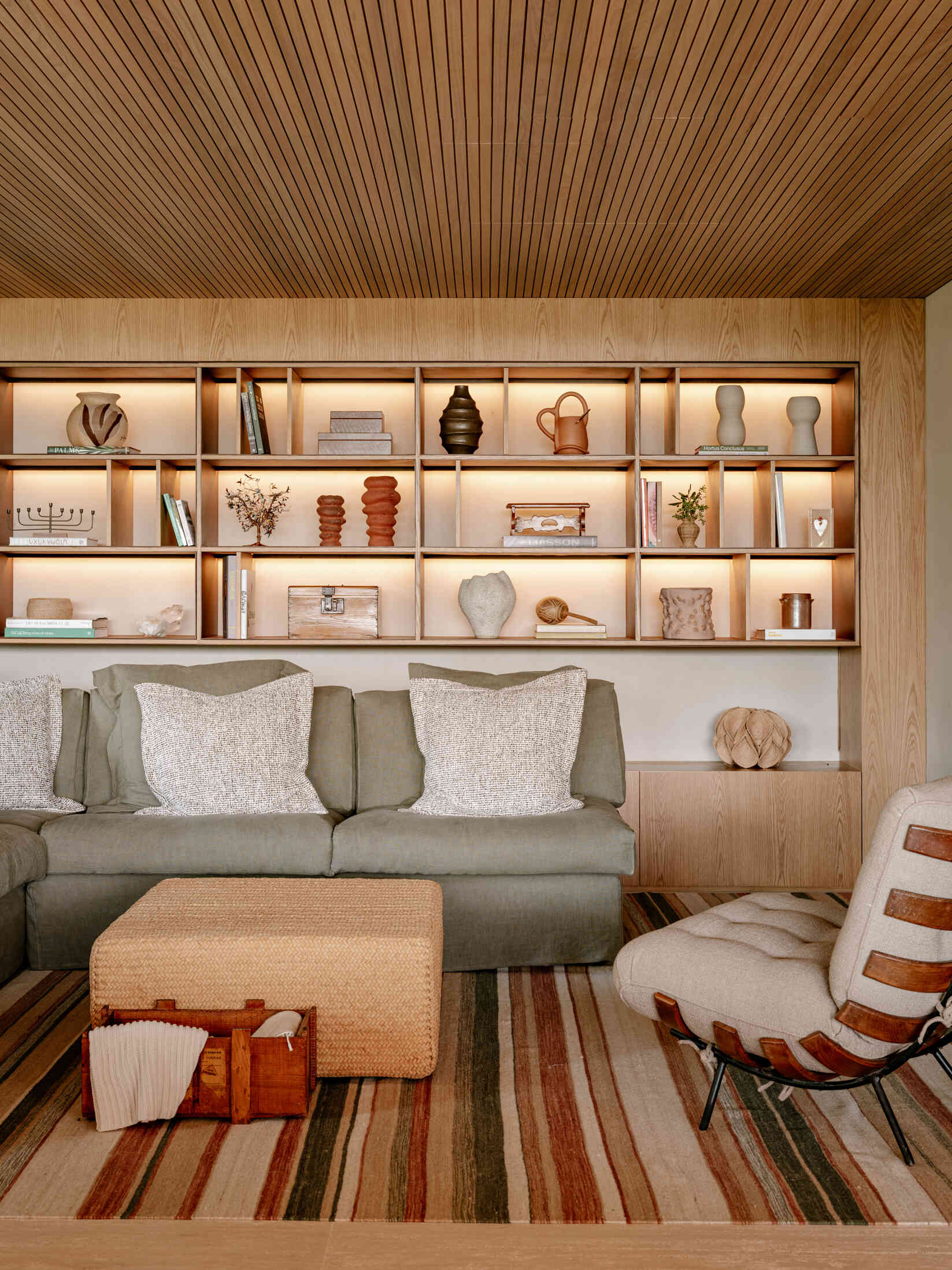 Vea cómo las tablas de madera plegadas y un llamativo sofá verde crean un espacio familiar acogedor lleno de calidez y color.