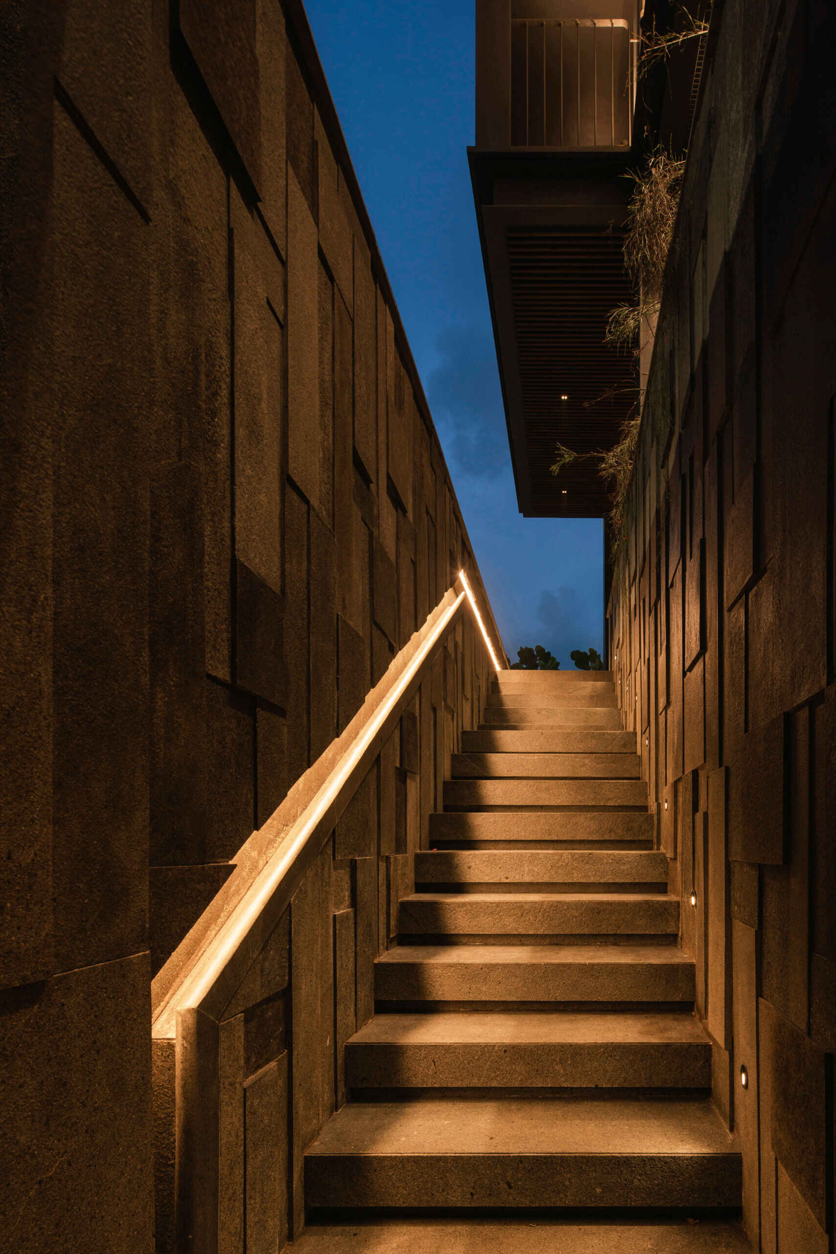 Exterior stairs connect the garage with the home's landscaped outdoor spaces while continuing the modern architectural design.