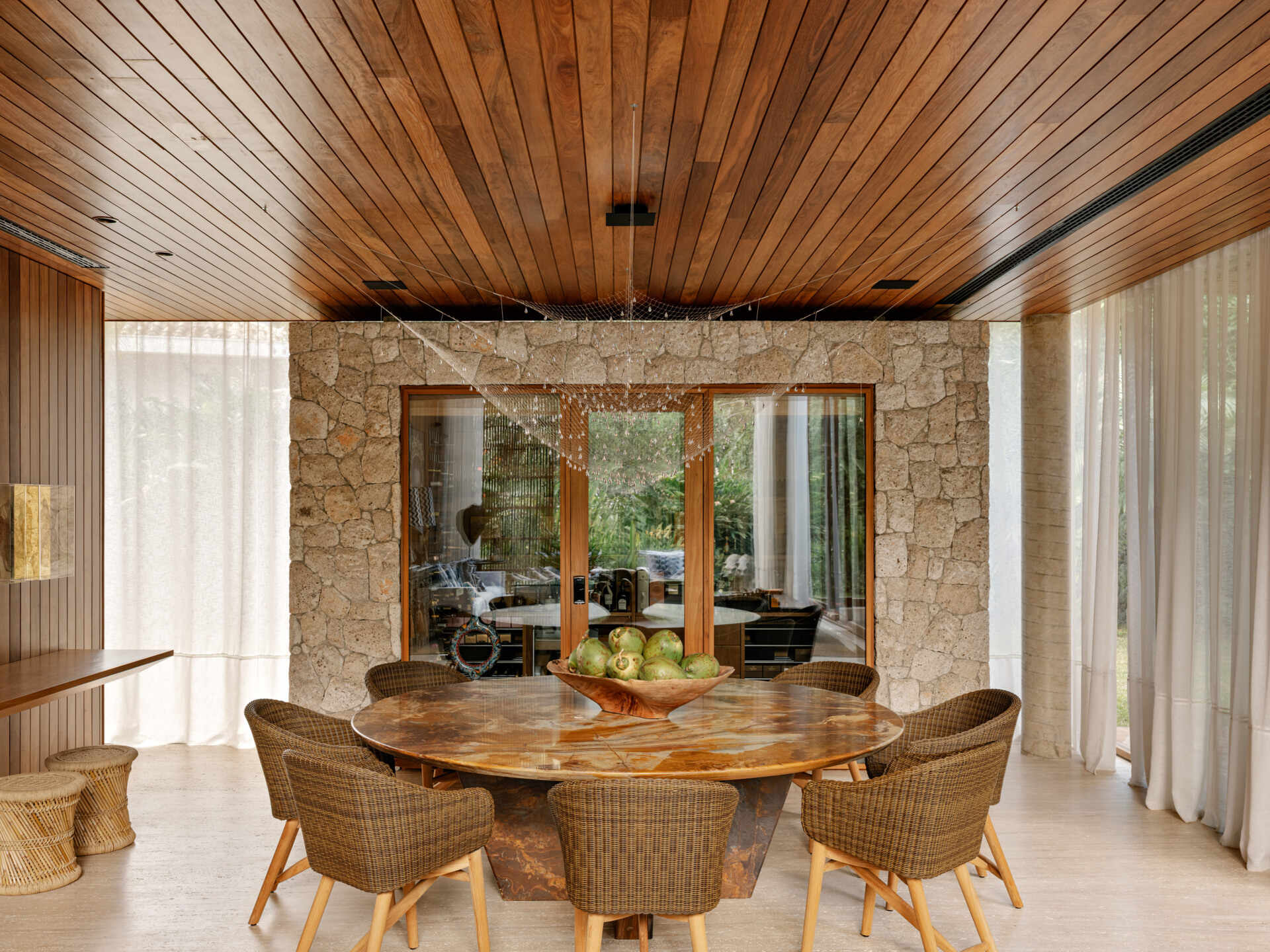 A custom stone dining table and sculptural lighting elevate this elegant coastal dining room.