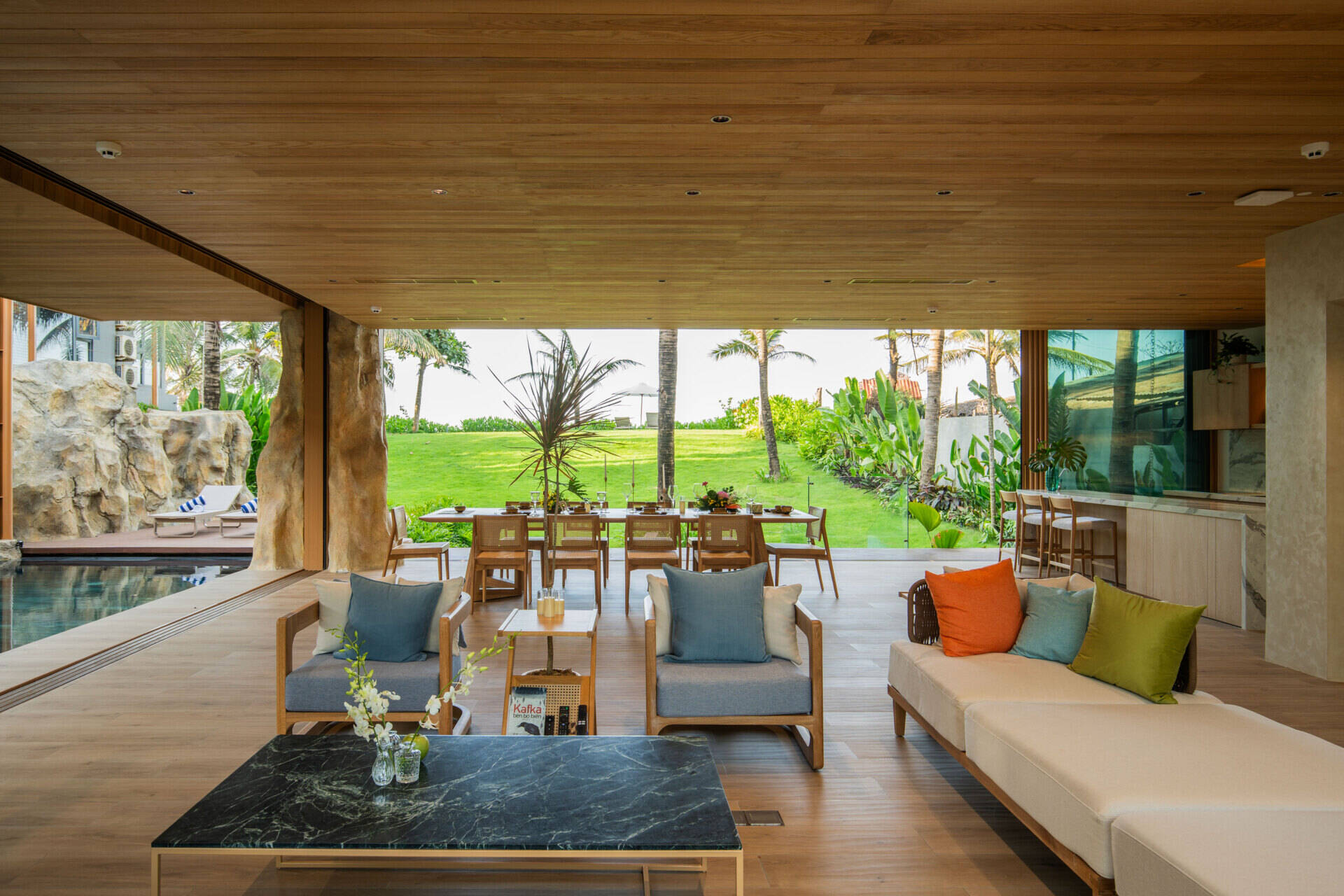 Large sliding glass doors and open-plan living create bright interiors that flow naturally toward the pool, gardens and ocean beyond.