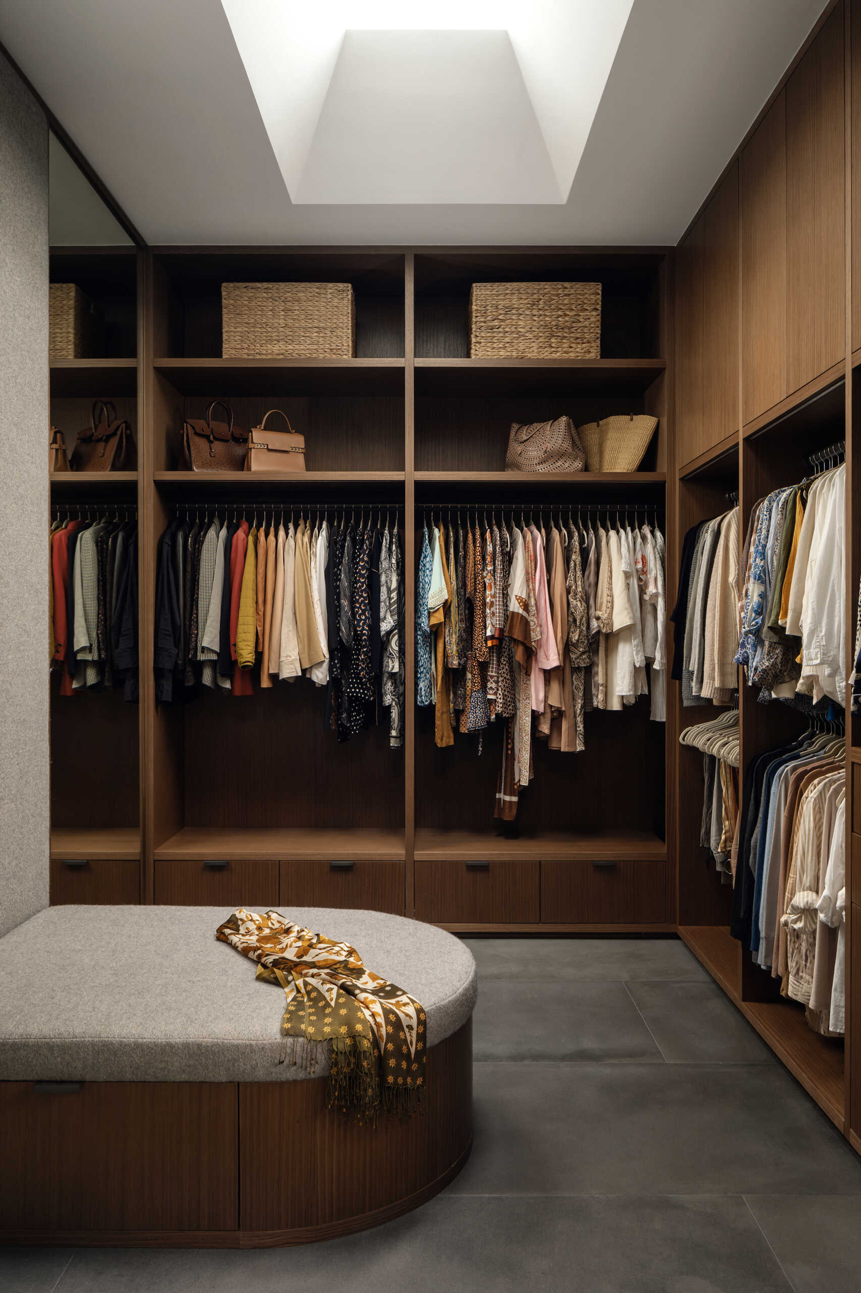 Walnut cabinetry and integrated storage create a clean, organised walk-in closet.