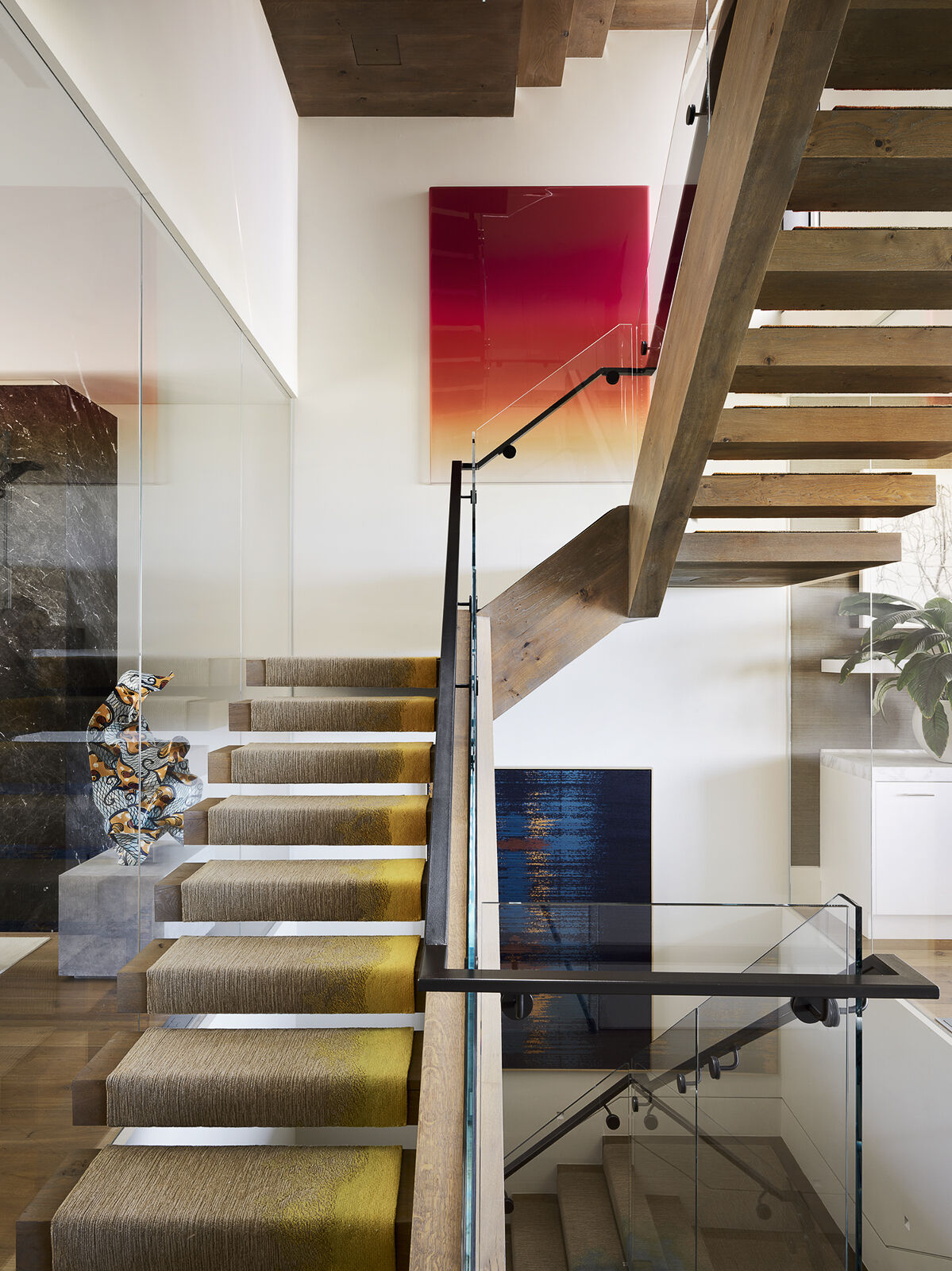 A vibrant stair runner transforms this staircase into the defining feature of the home, weaving a spectrum of color through every level. Paired with contemporary artwork, it creates a bold visual thread that connects the entire interior while turning a functional space into a striking design statement.