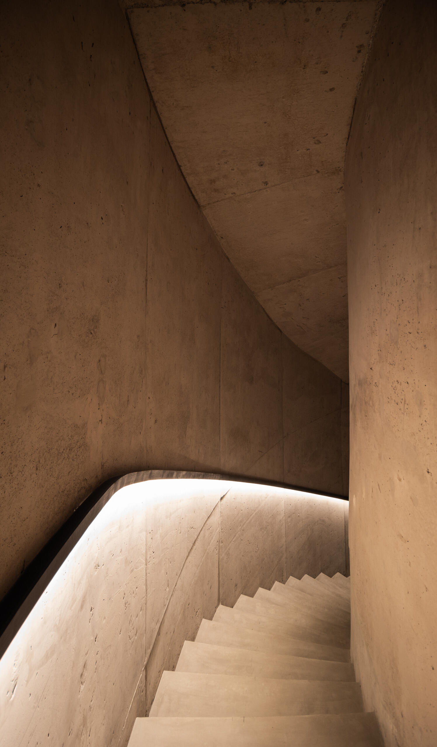 See how an interior concrete staircase with hidden lighting creates a smooth connection between floors.