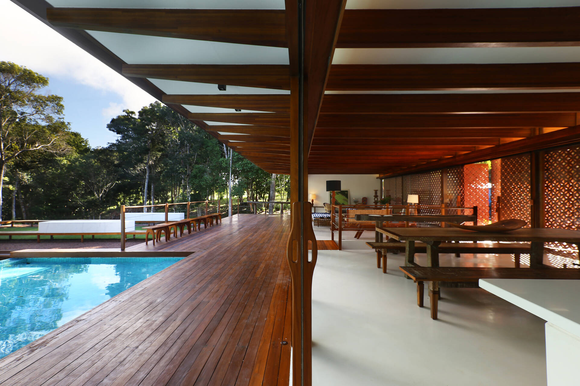 Inside, a 78 foot (24-metre) open-plan living space combines custom furniture, artisan lighting and seamless white cement floors beneath exposed timber beams.