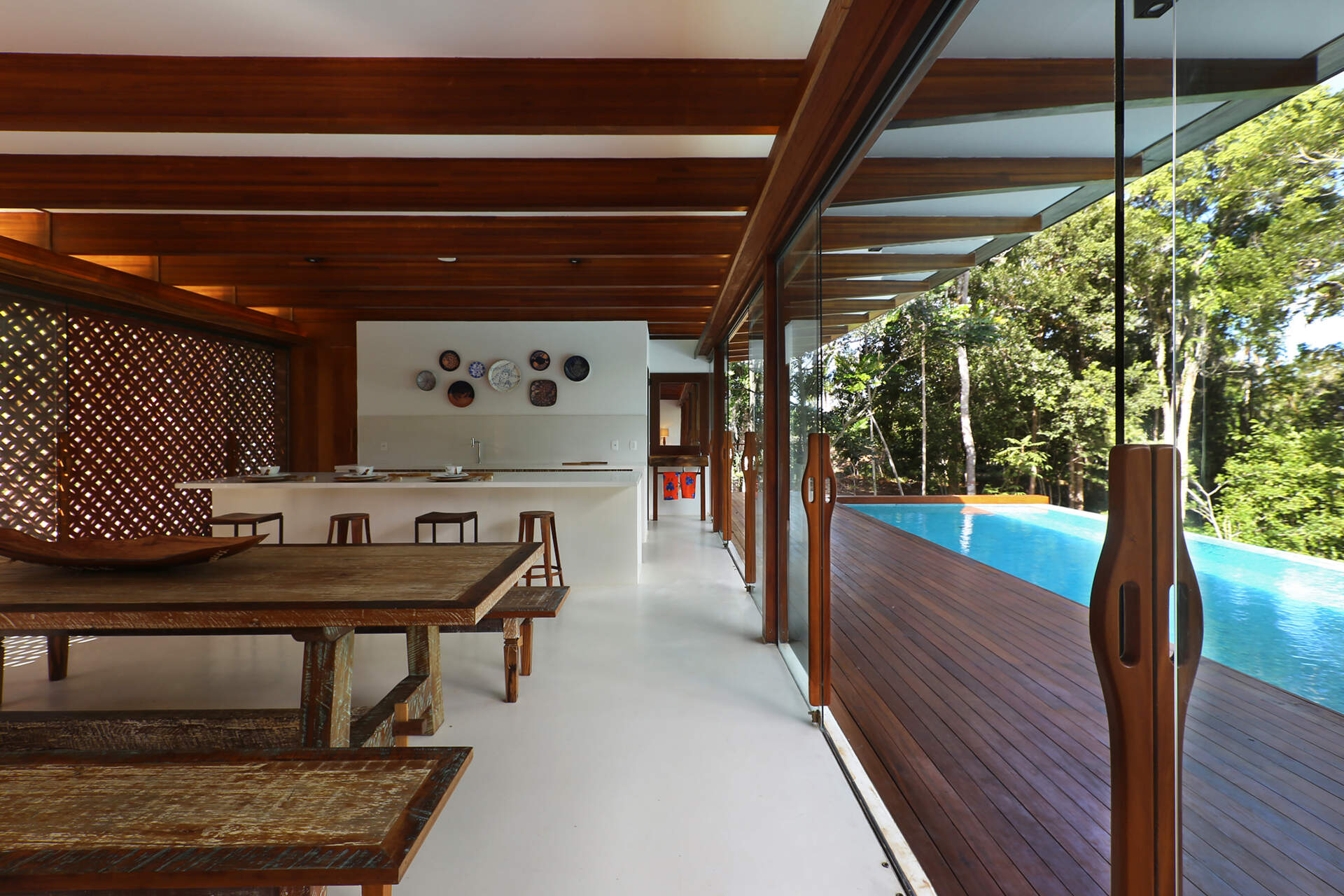 Inside, a 78 foot (24-metre) open-plan living space combines custom furniture, artisan lighting and seamless white cement floors beneath exposed timber beams.