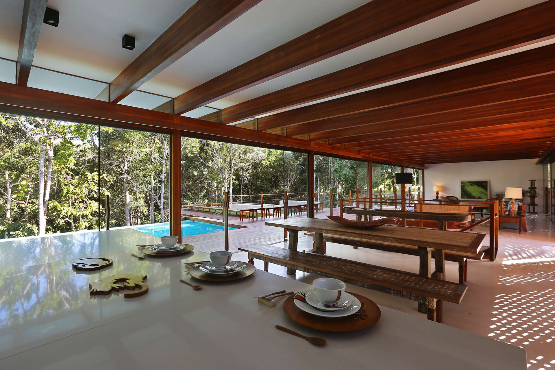 Inside, a 78 foot (24-metre) open-plan living space combines custom furniture, artisan lighting and seamless white cement floors beneath exposed timber beams.