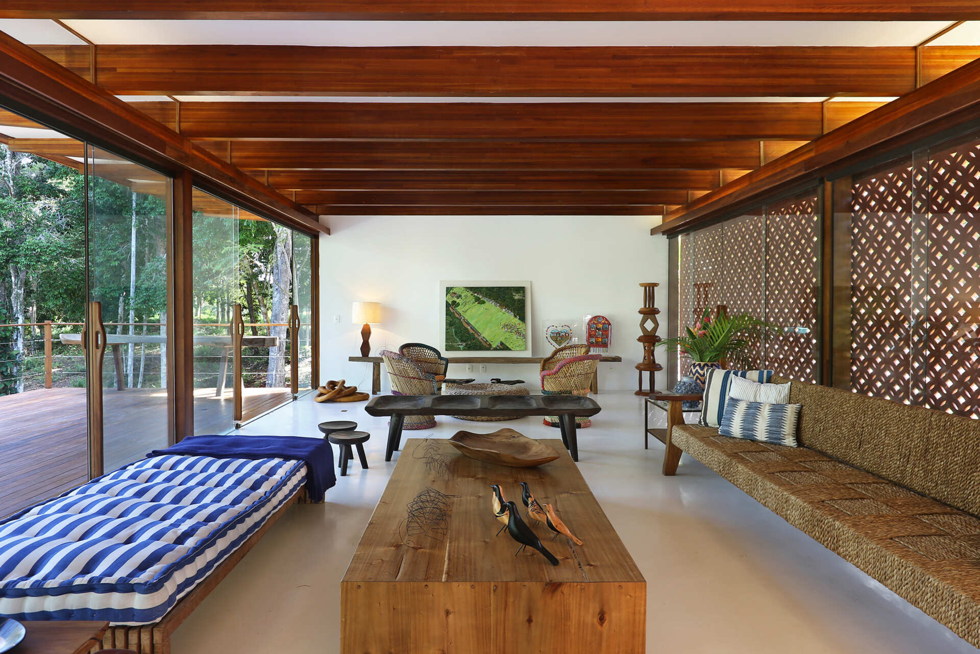 Inside, a 78 foot (24-metre) open-plan living space combines custom furniture, artisan lighting and seamless white cement floors beneath exposed timber beams.
