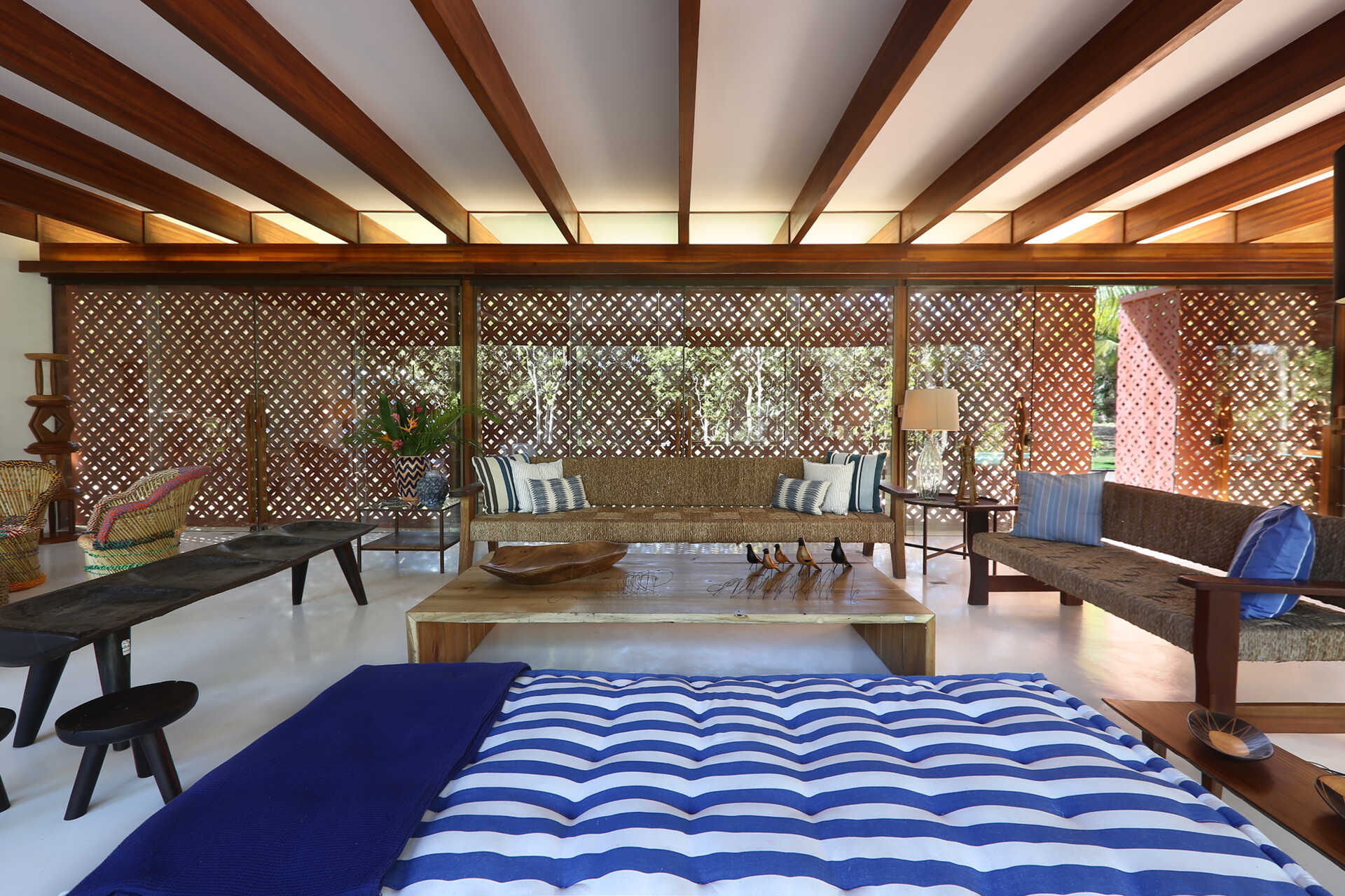 Inside, a 78 foot (24-metre) open-plan living space combines custom furniture, artisan lighting and seamless white cement floors beneath exposed timber beams.