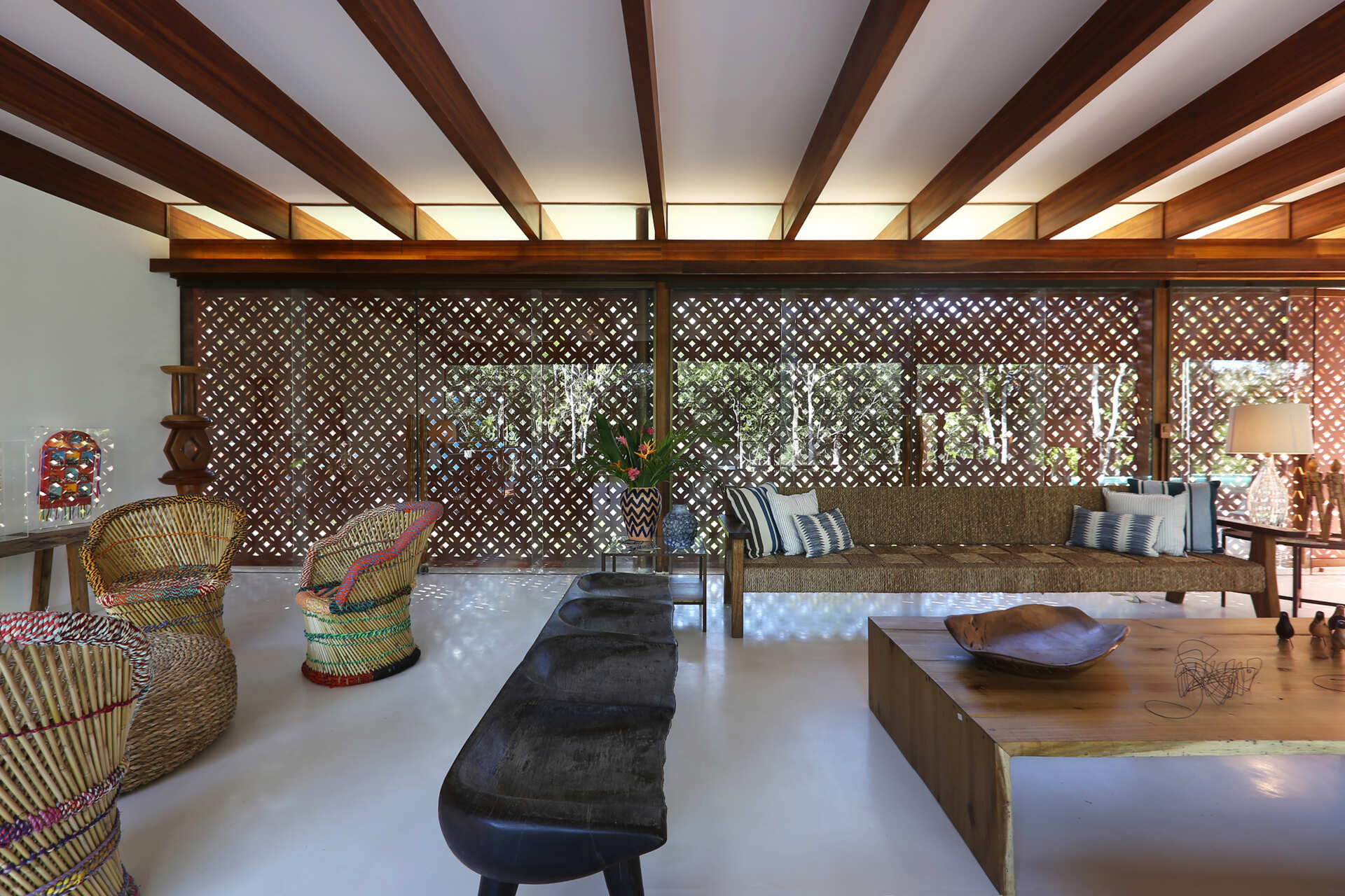 Inside, a 78 foot (24-metre) open-plan living space combines custom furniture, artisan lighting and seamless white cement floors beneath exposed timber beams.