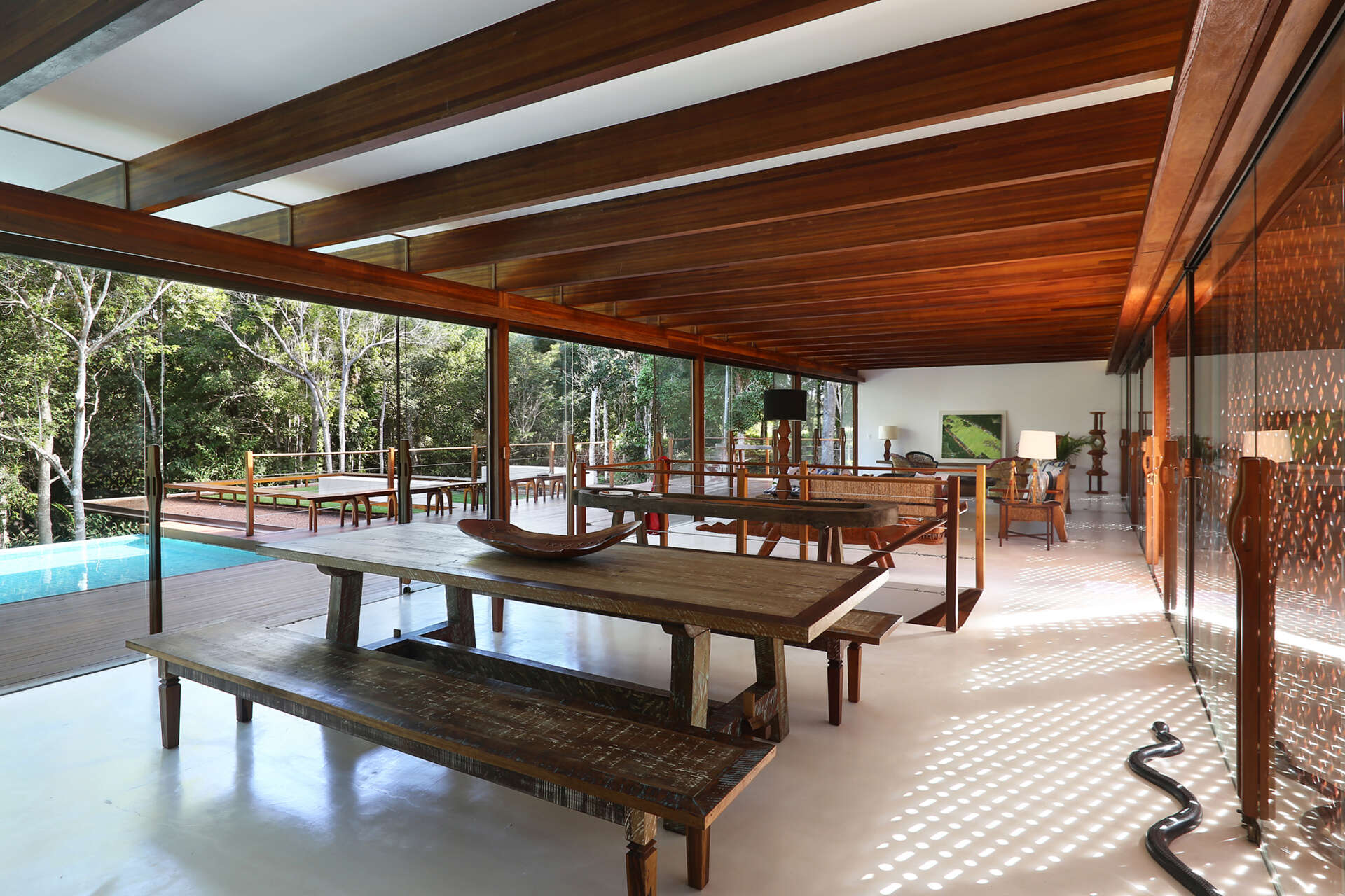 Inside, a 78 foot (24-metre) open-plan living space combines custom furniture, artisan lighting and seamless white cement floors beneath exposed timber beams.
