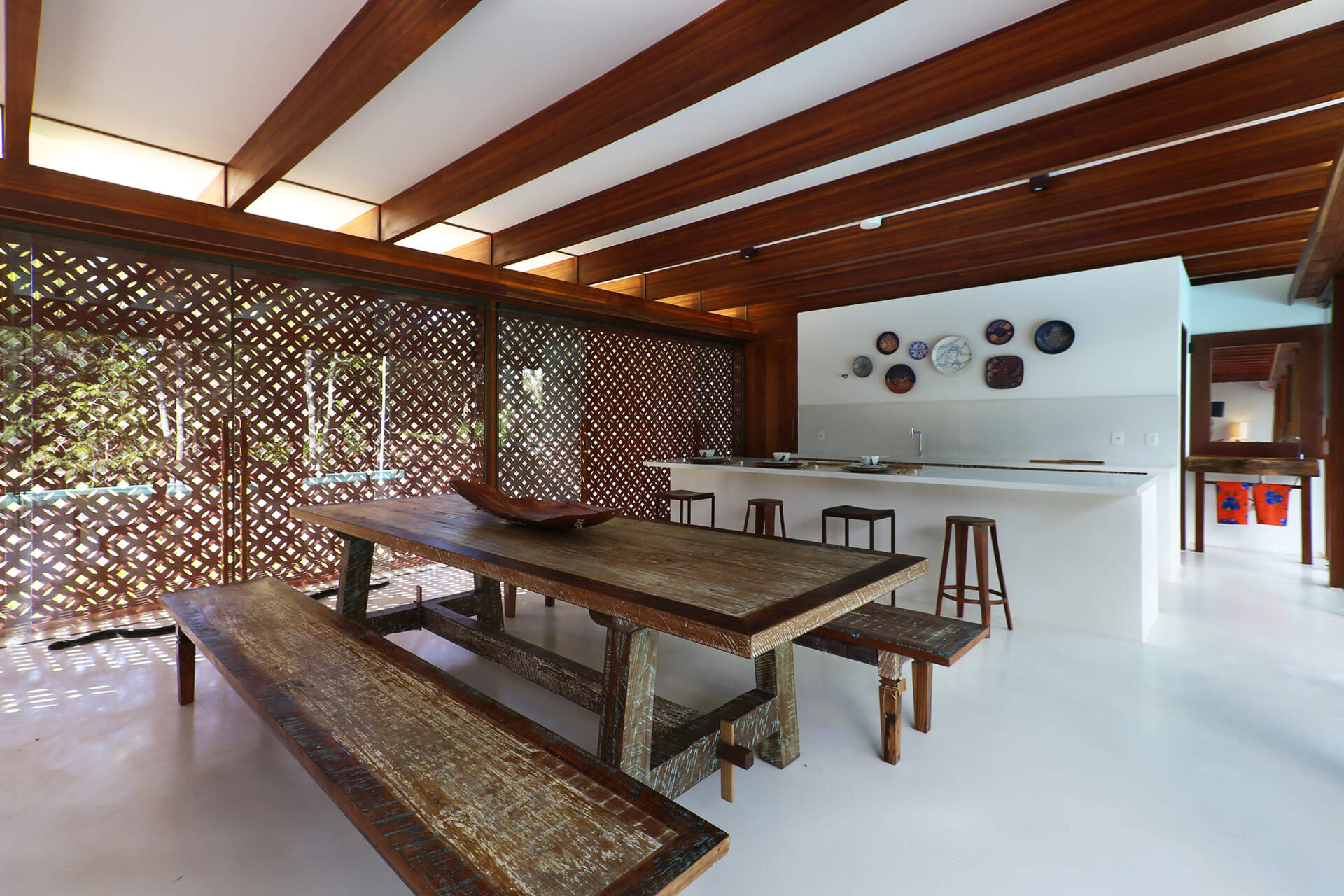 Inside, a 78 foot (24-metre) open-plan living space combines custom furniture, artisan lighting and seamless white cement floors beneath exposed timber beams.