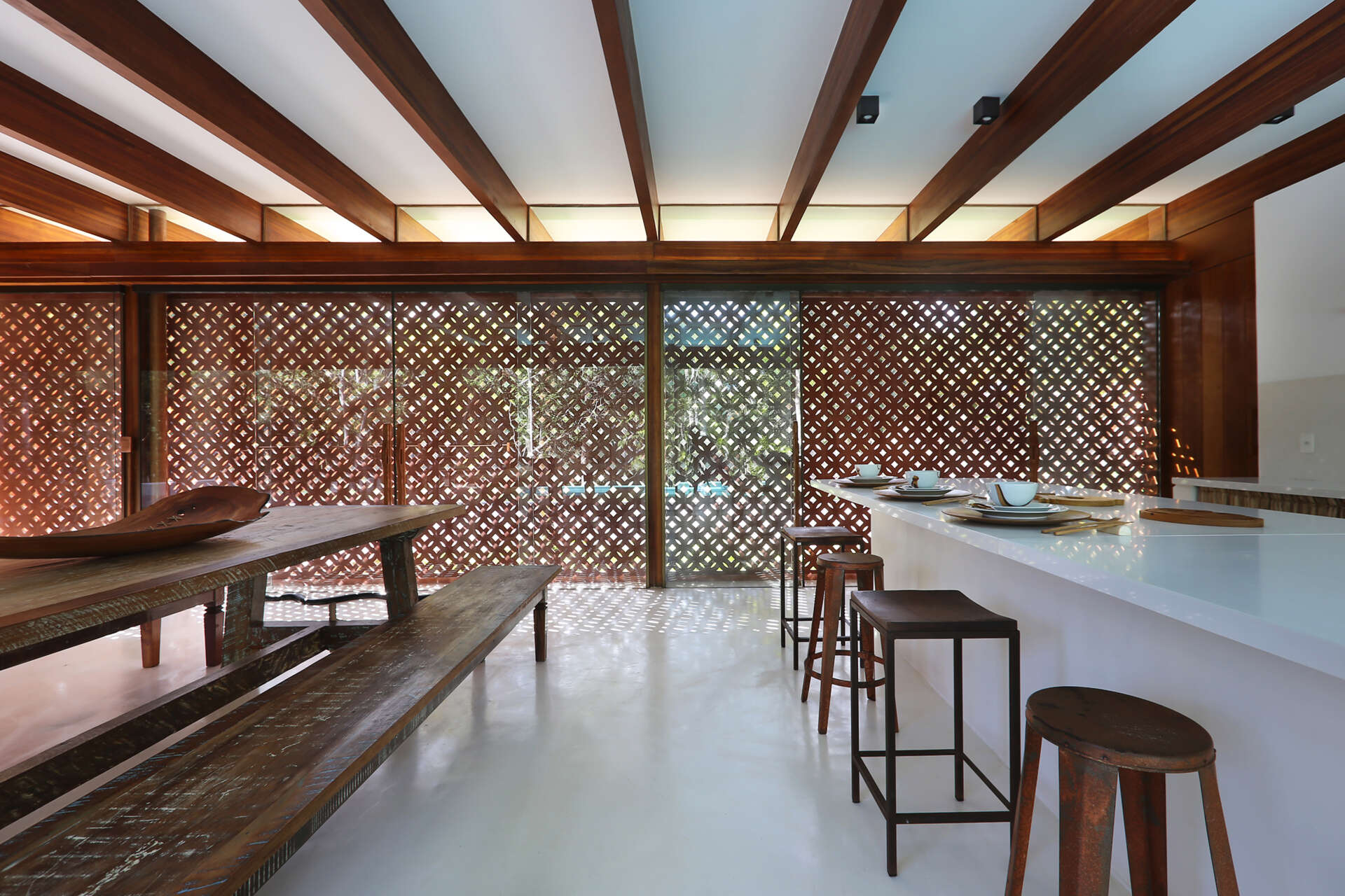 Inside, a 78 foot (24-metre) open-plan living space combines custom furniture, artisan lighting and seamless white cement floors beneath exposed timber beams.
