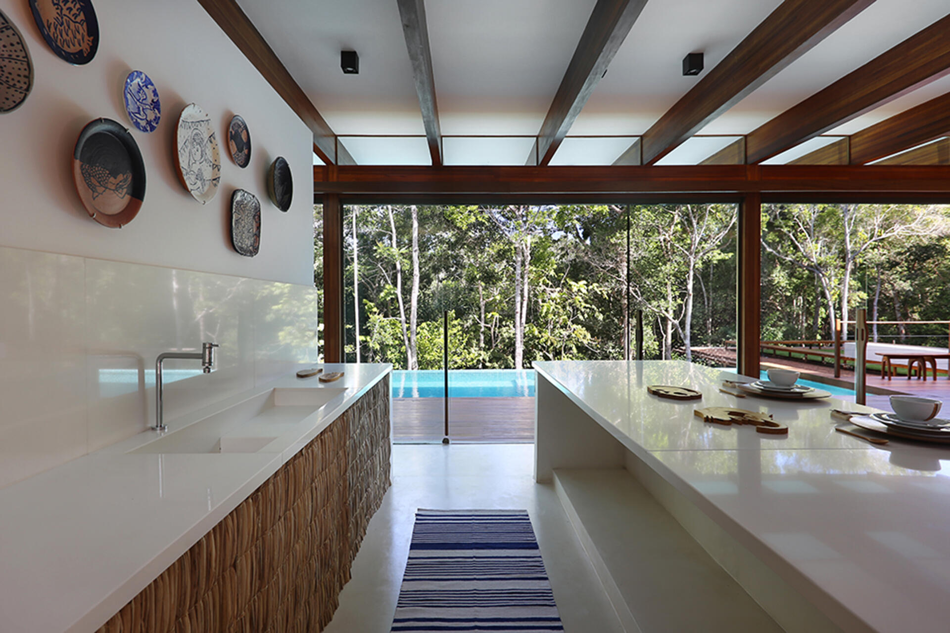 Inside, a 78 foot (24-metre) open-plan living space combines custom furniture, artisan lighting and seamless white cement floors beneath exposed timber beams.
