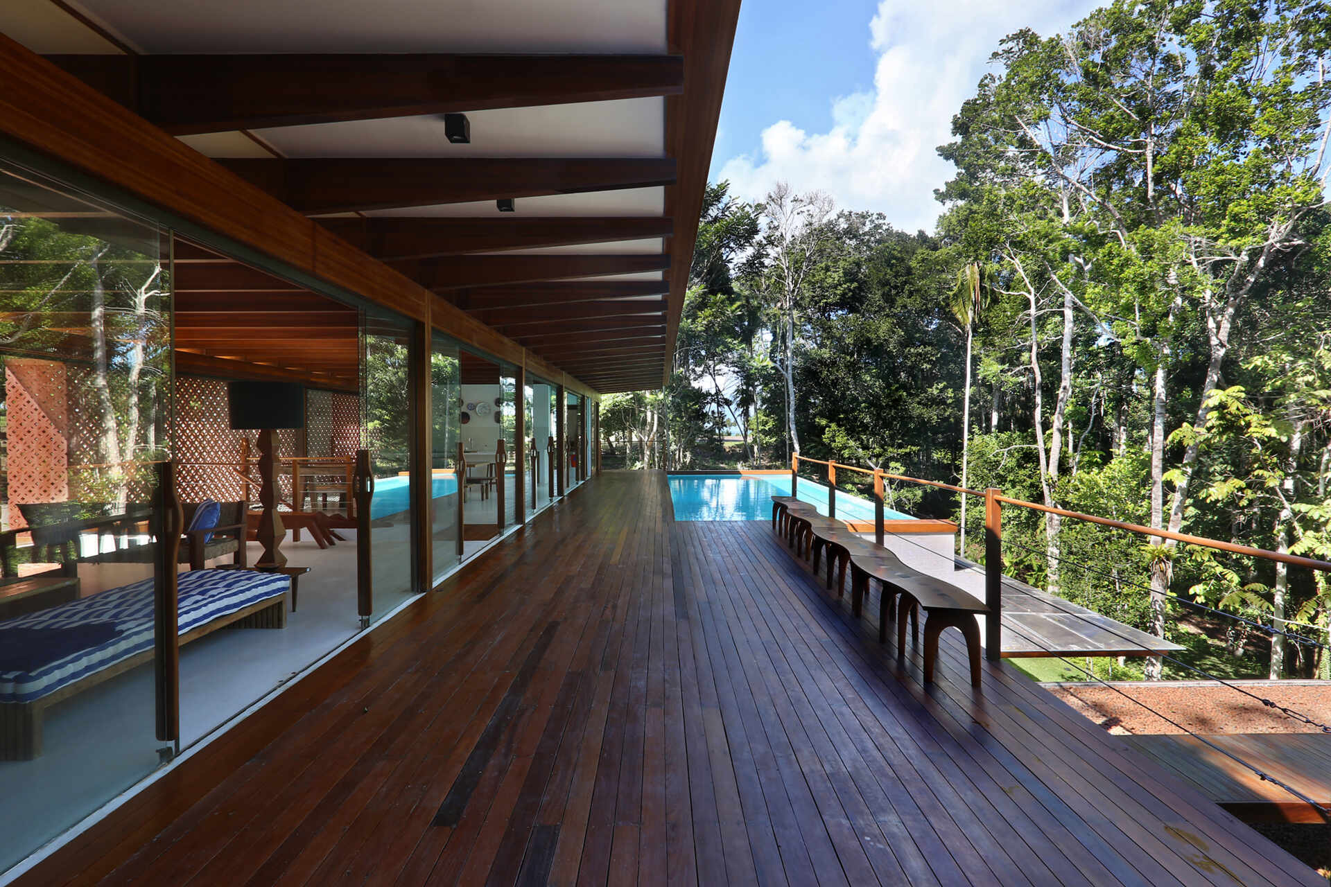 An infinity pool floats above the Atlantic Forest while a generous timber deck and wraparound bench create the perfect outdoor entertaining space.