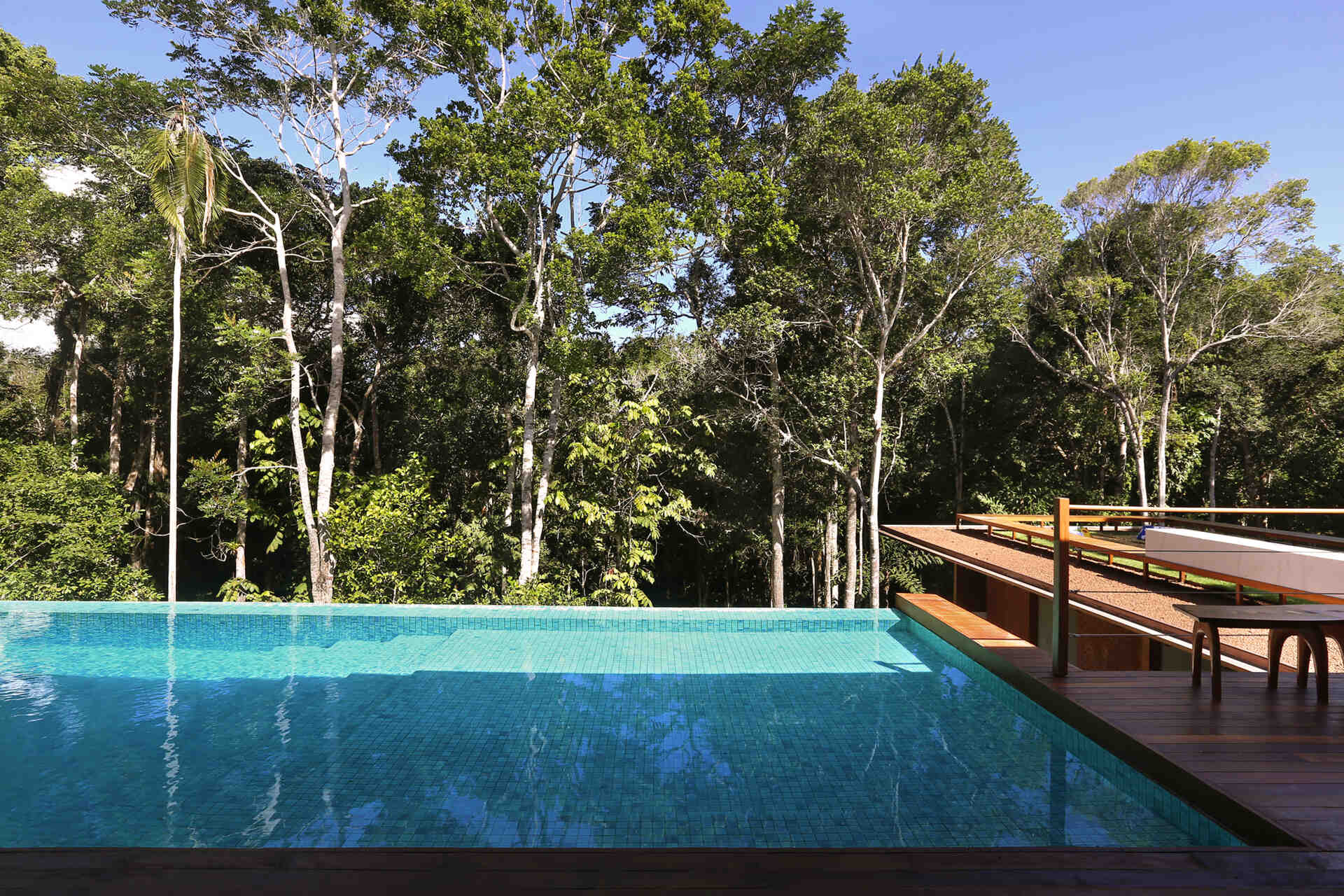 An infinity pool floats above the Atlantic Forest while a generous timber deck and wraparound bench create the perfect outdoor entertaining space.