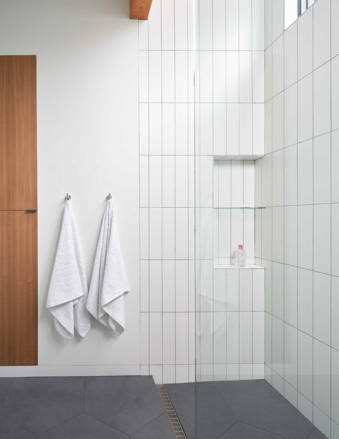 This updated bathroom combine warm wood details, full-height subway tiles, and abundant natural light to create clean, contemporary spaces.