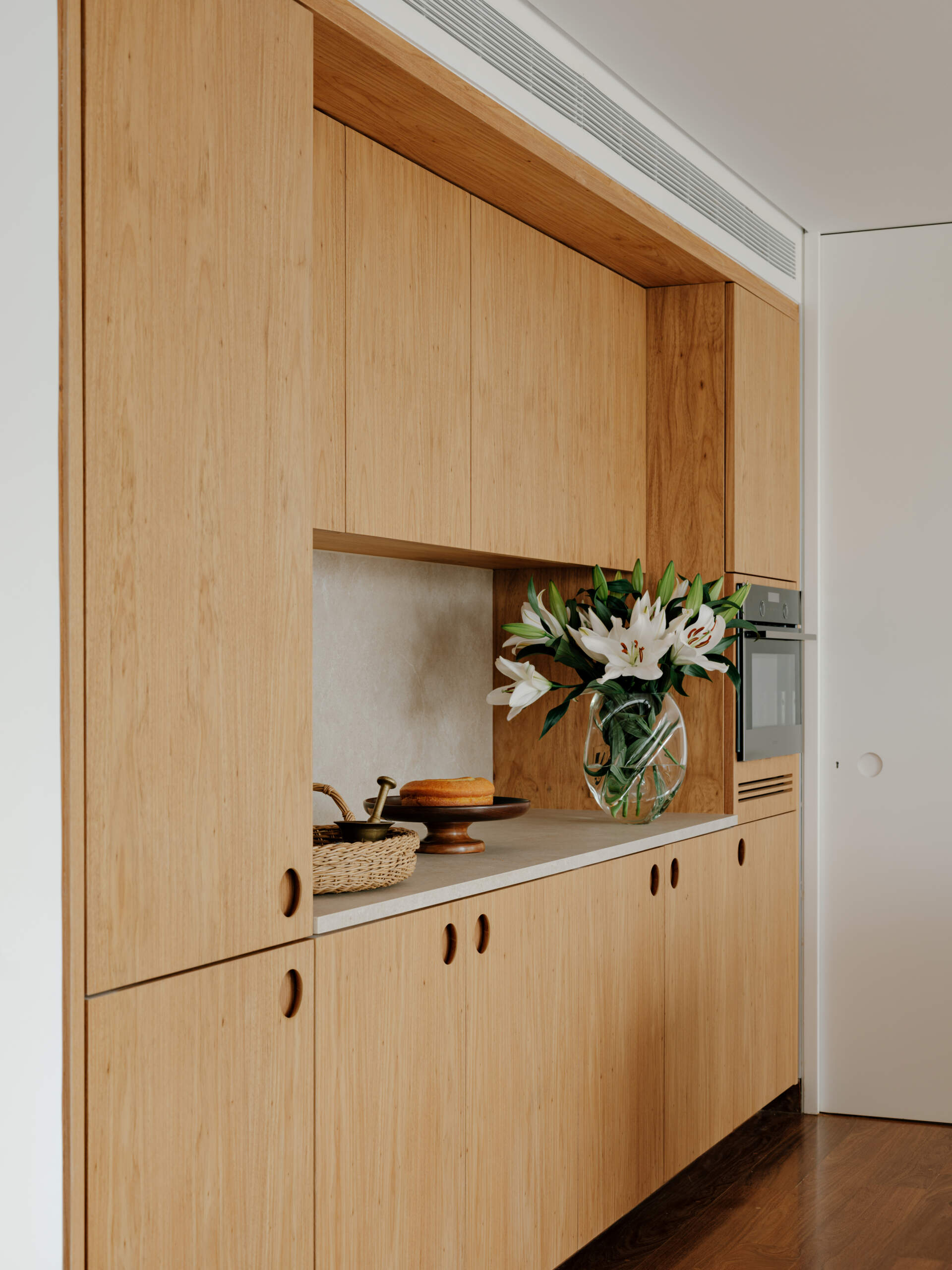 See how sliding doors, timber cabinetry and stone surfaces create a flexible kitchen that feels open yet practical.
