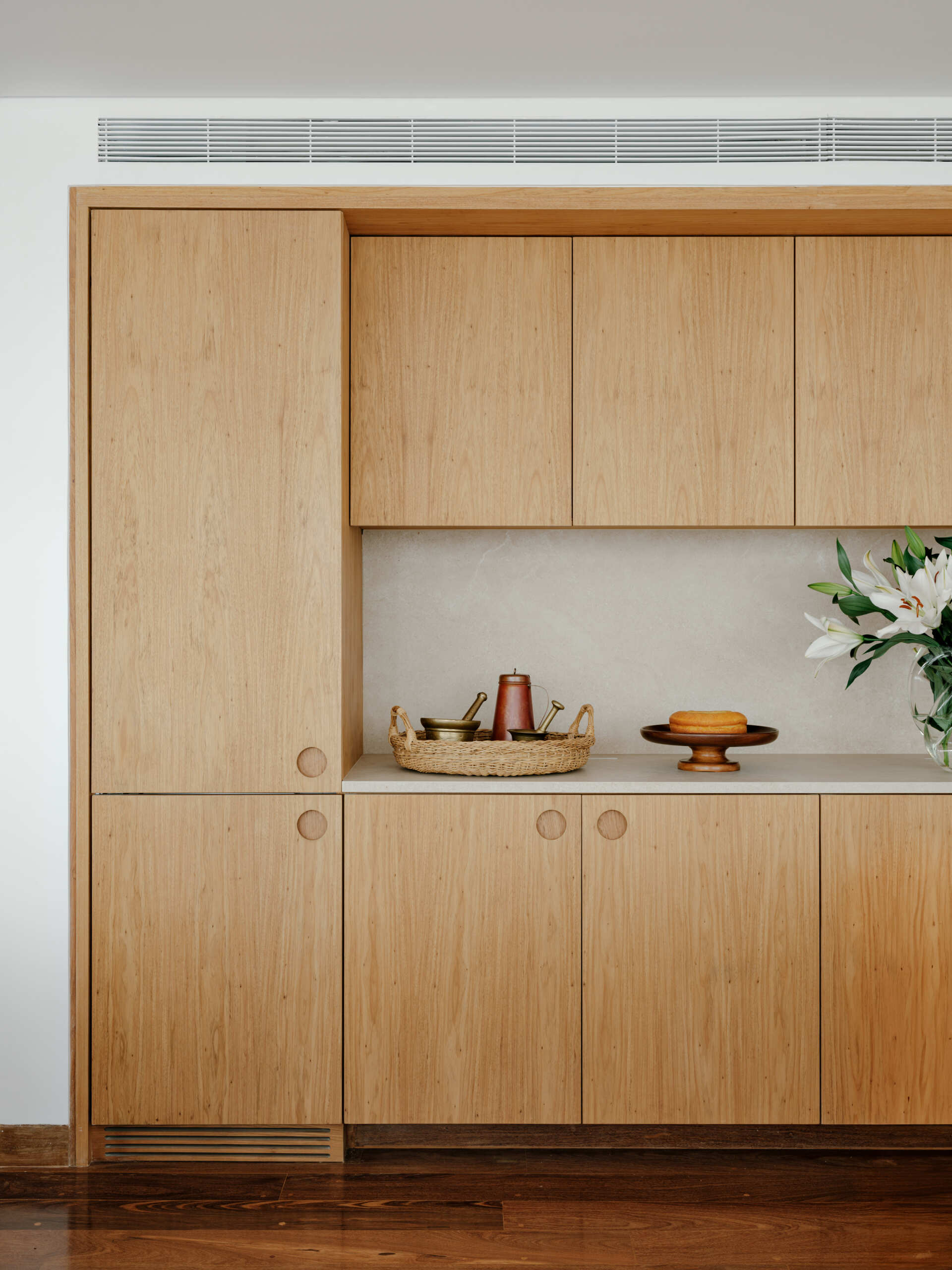 See how sliding doors, timber cabinetry and stone surfaces create a flexible kitchen that feels open yet practical.