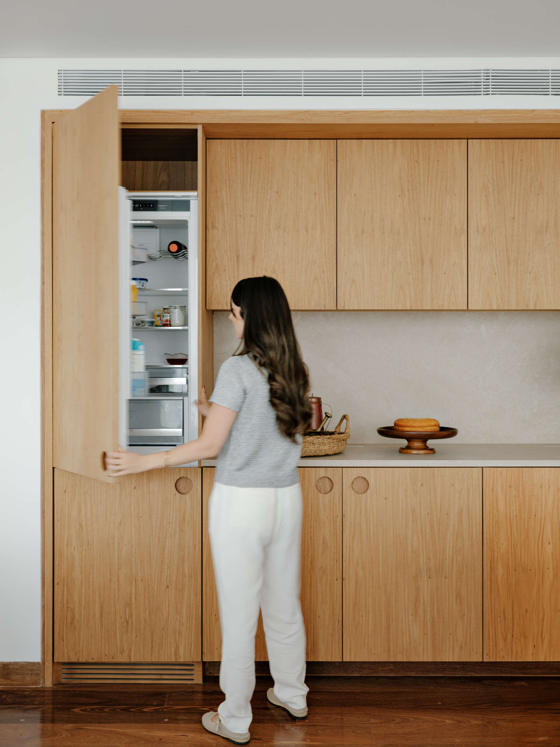 See how sliding doors, timber cabinetry and stone surfaces create a flexible kitchen that feels open yet practical.