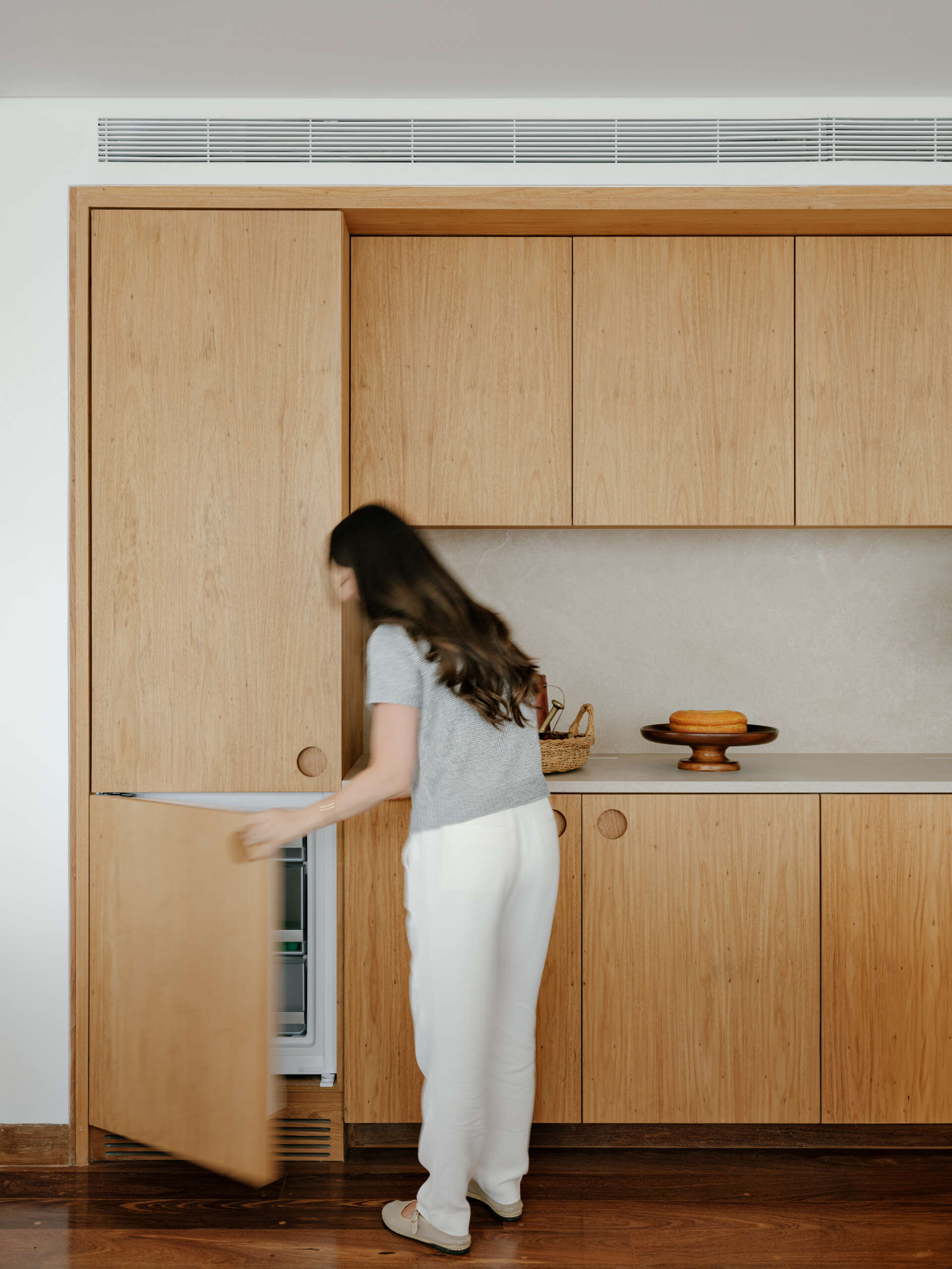 See how sliding doors, timber cabinetry and stone surfaces create a flexible kitchen that feels open yet practical.
