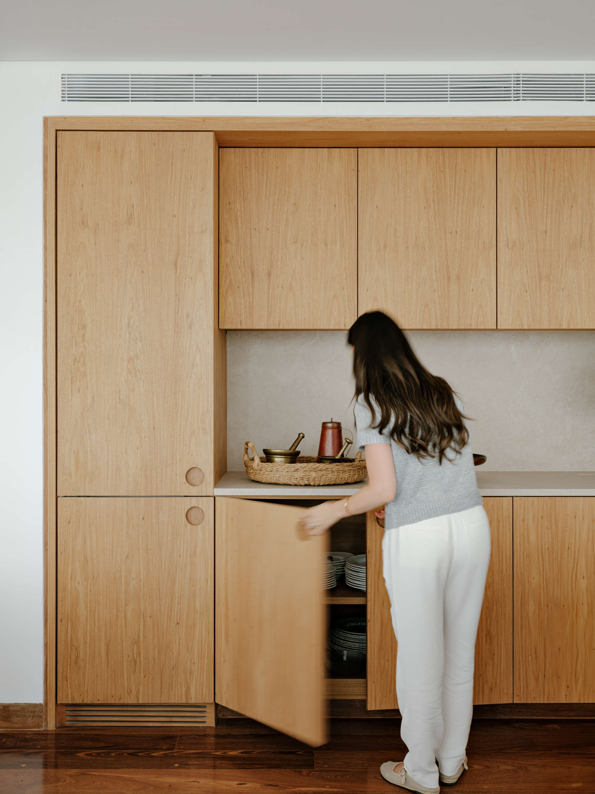 See how sliding doors, timber cabinetry and stone surfaces create a flexible kitchen that feels open yet practical.