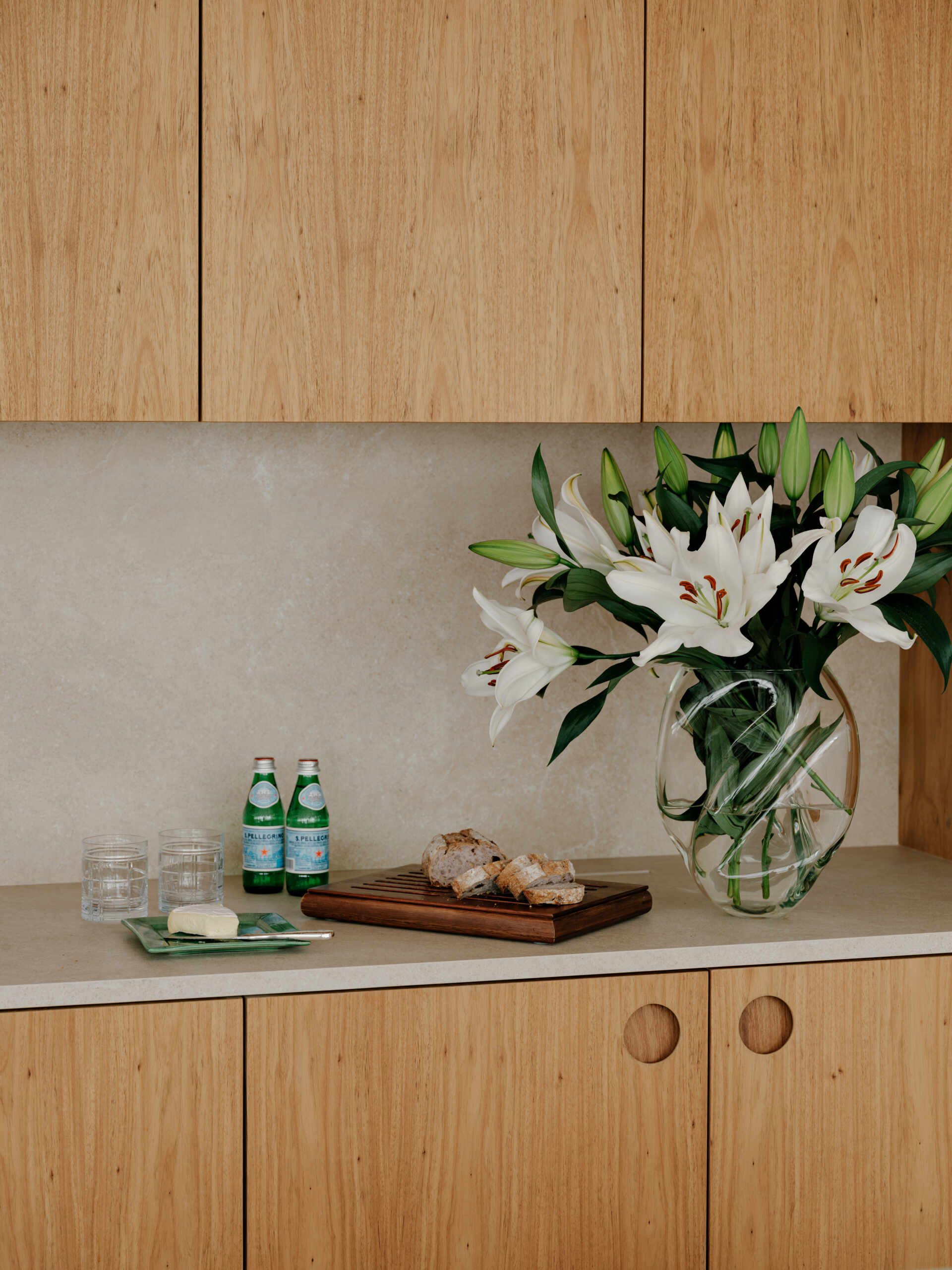 See how sliding doors, timber cabinetry and stone surfaces create a flexible kitchen that feels open yet practical.