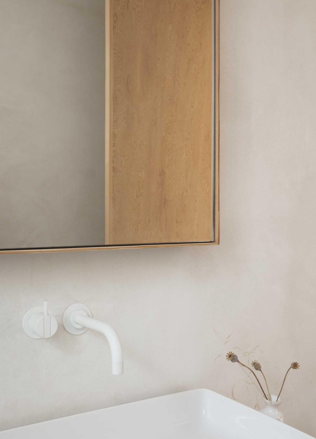 Small square tiles wrap the bath and shower area while timber accents around the mirror and vanity bring warmth to this compact contemporary bathroom.
