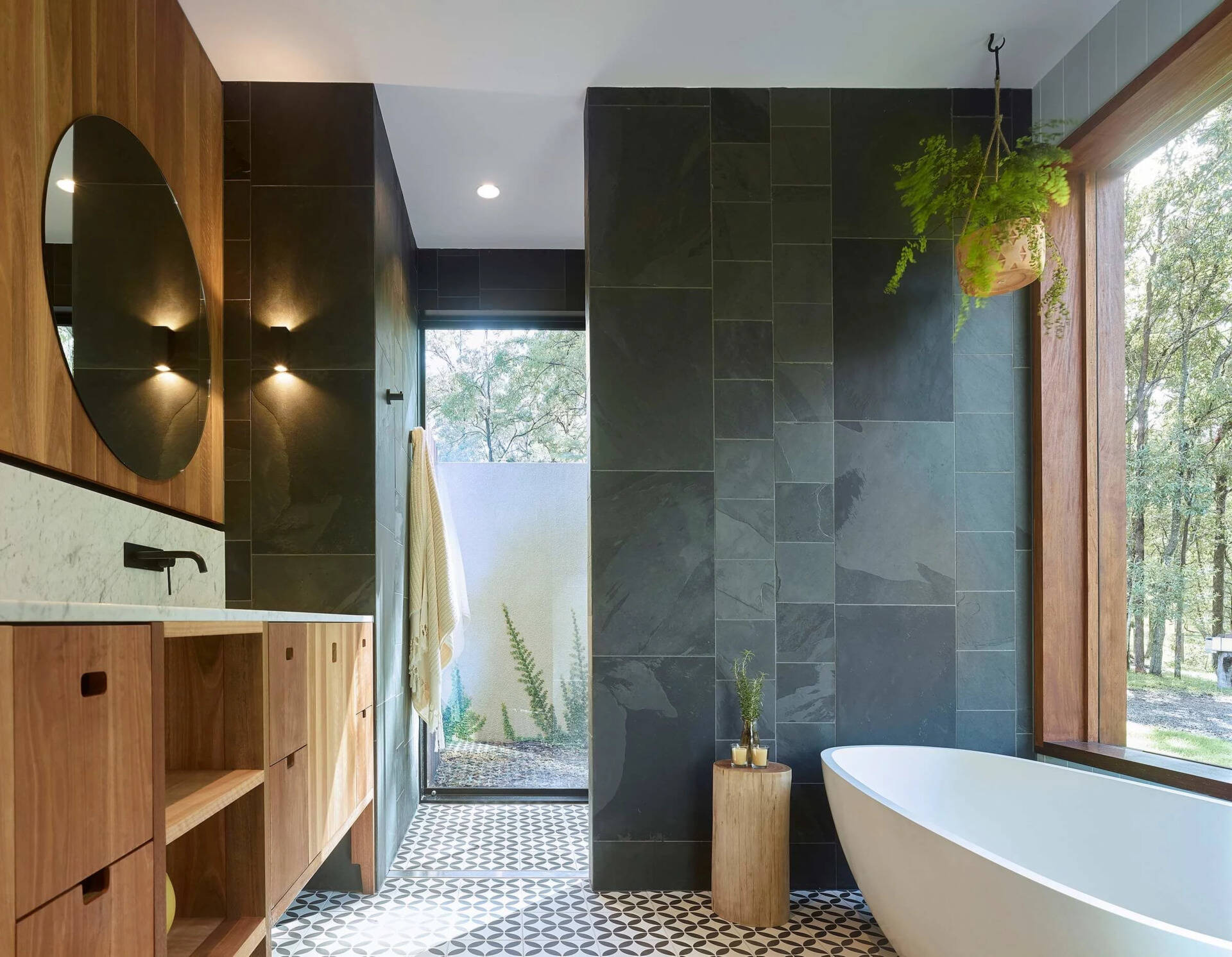 This light-filled bathroom pairs frosted glass with a large picture window overlooking the trees.
