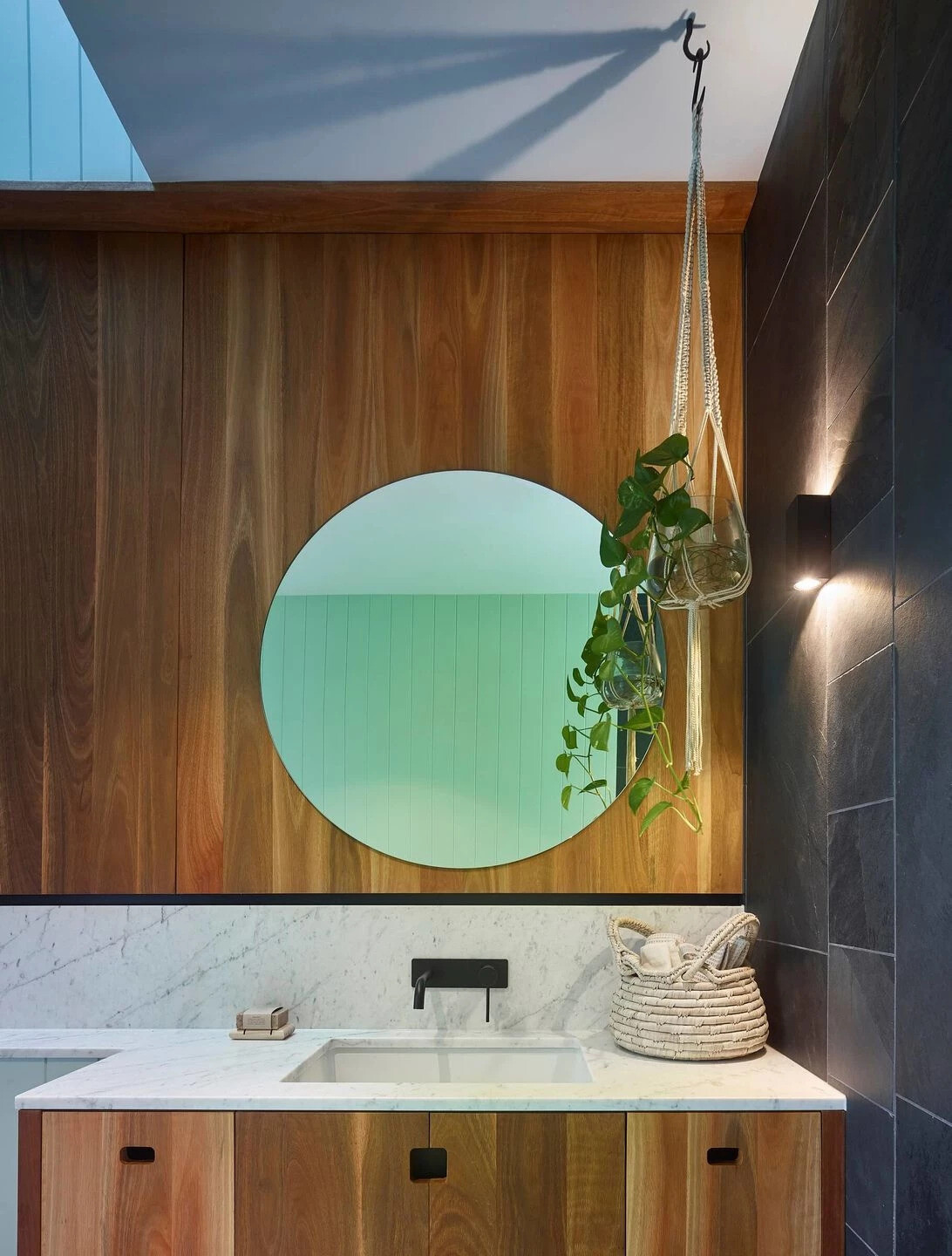 This light-filled bathroom pairs frosted glass with a large picture window overlooking the trees.