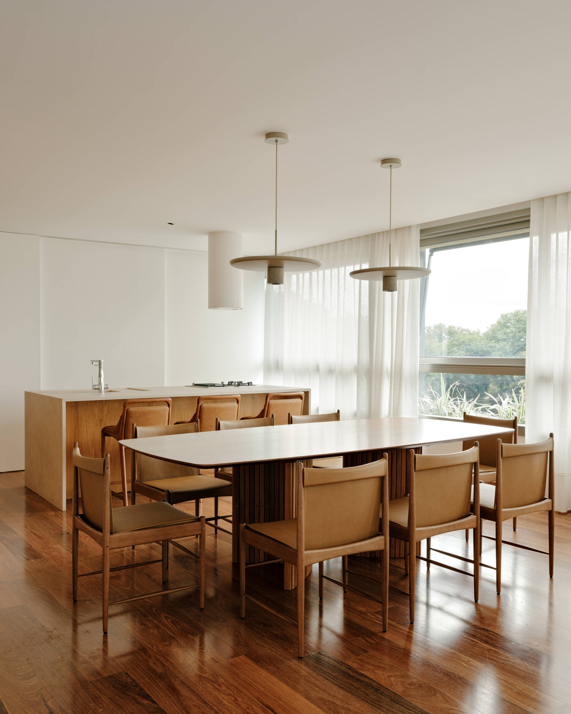 Warm timber, caramel leather and elegant lighting create a dining room that's both refined and inviting.