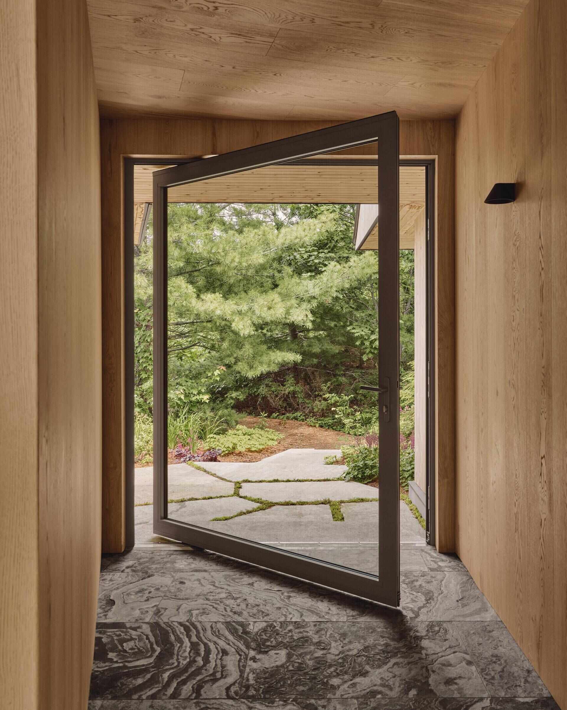 A large pivoting glass door connects the interior to the outdoors.