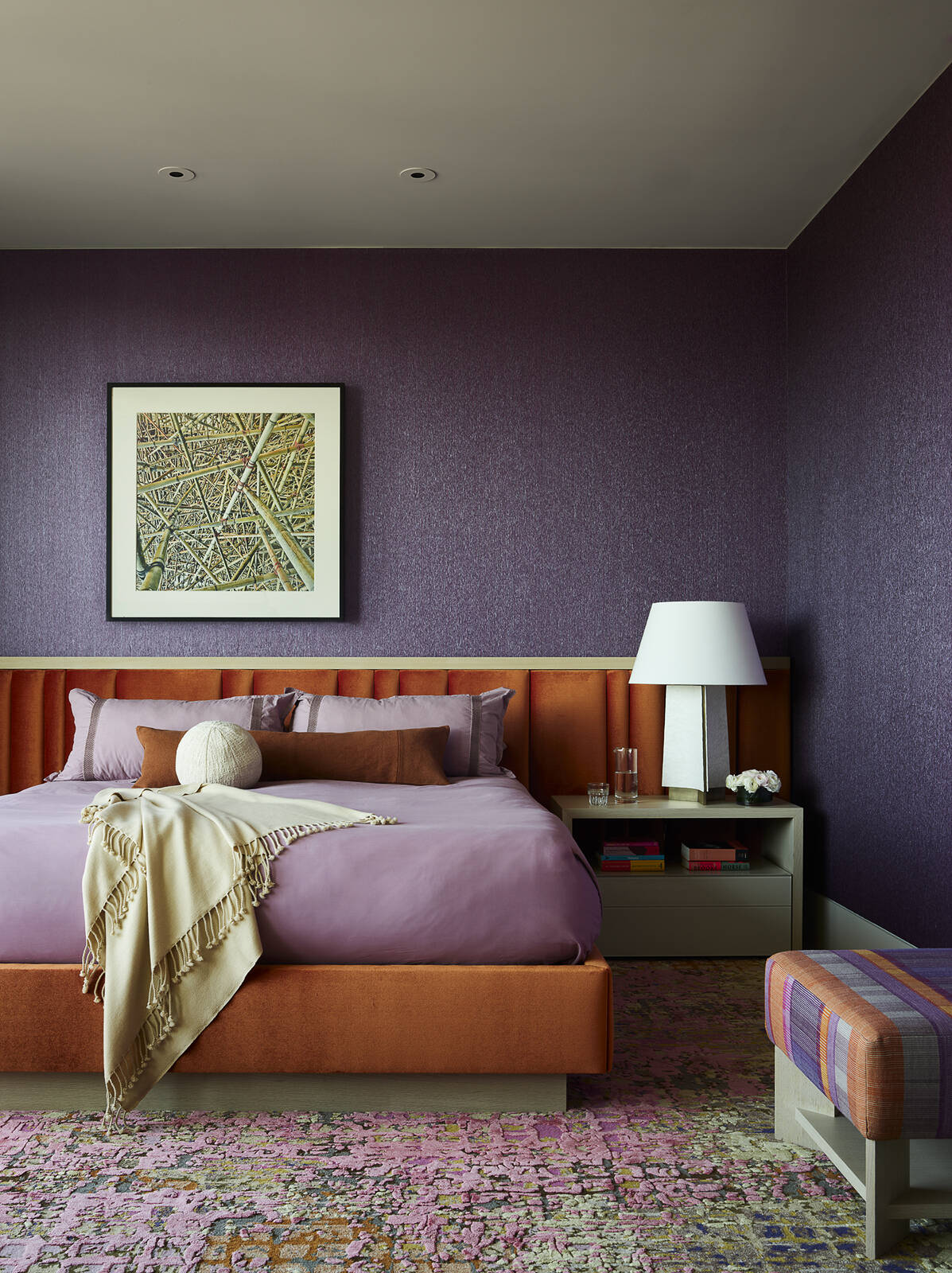 Deep plum walls, warm earthy tones, and layered textures transform this bedroom into a calm and inviting retreat. Discover how bold color choices can create a sophisticated and restful space.