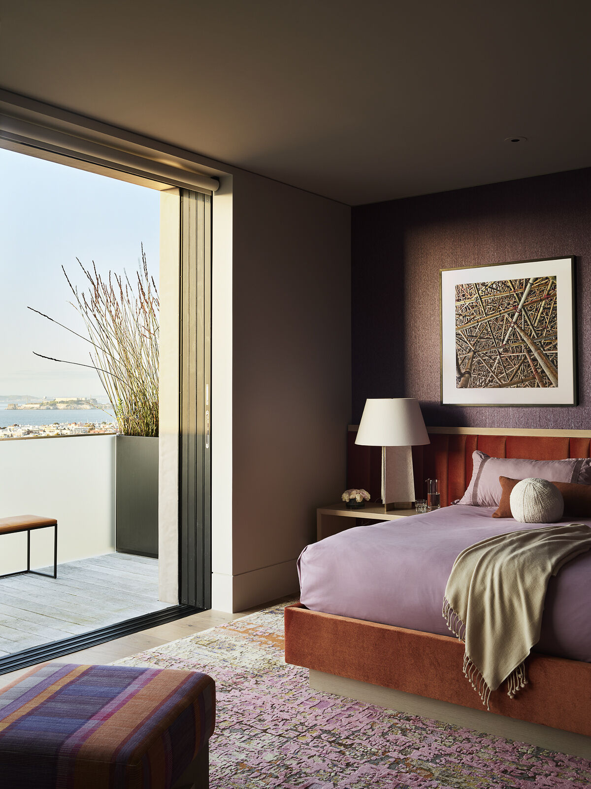 Deep plum walls, warm earthy tones, and layered textures transform this bedroom into a calm and inviting retreat. Discover how bold color choices can create a sophisticated and restful space.