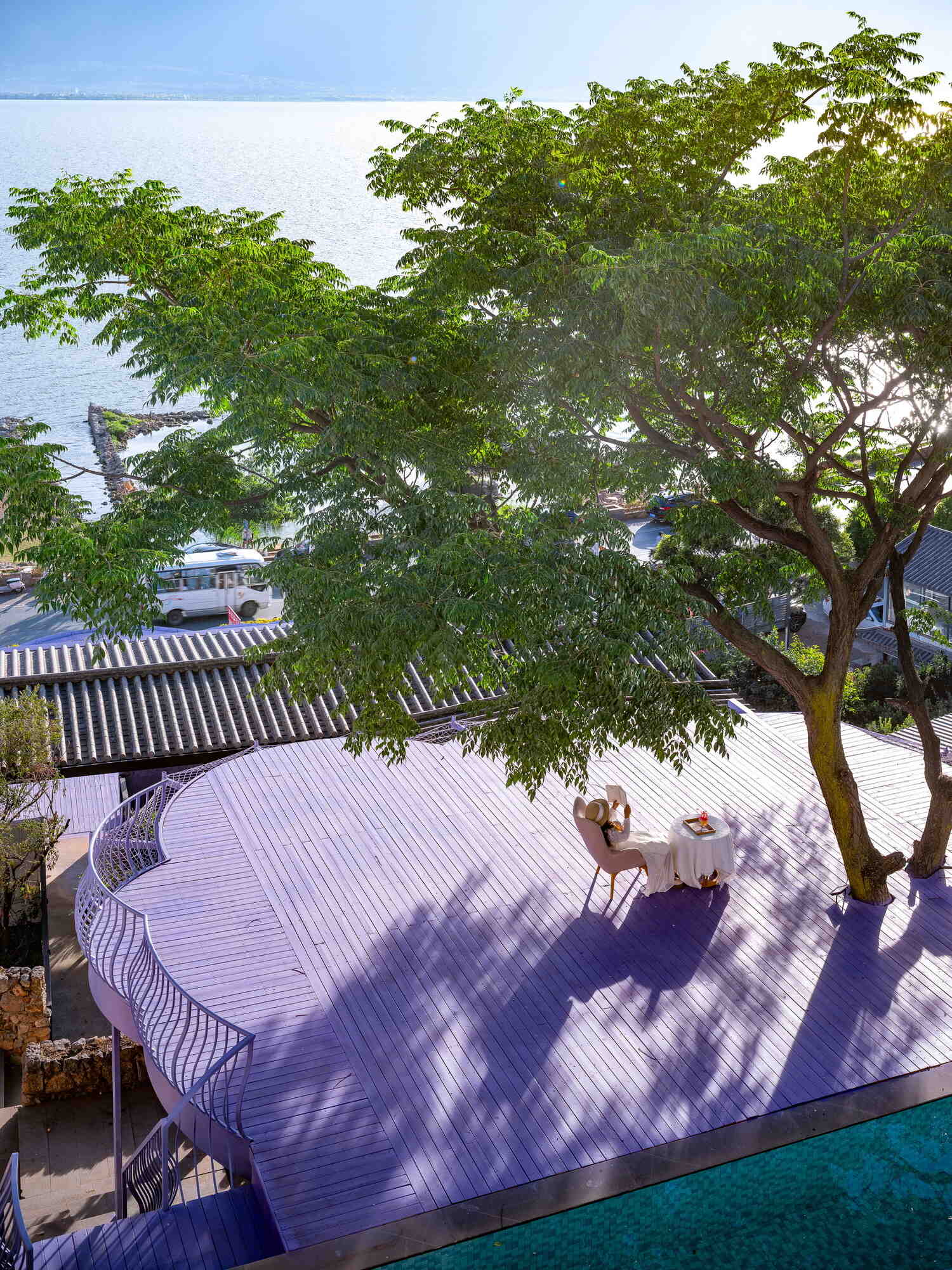 A mature tree becomes the centerpiece of the guesthouse thanks to flowing violet viewing platforms overlooking the Cangshan Mountains, Erhai Lake and the reflective pool.
