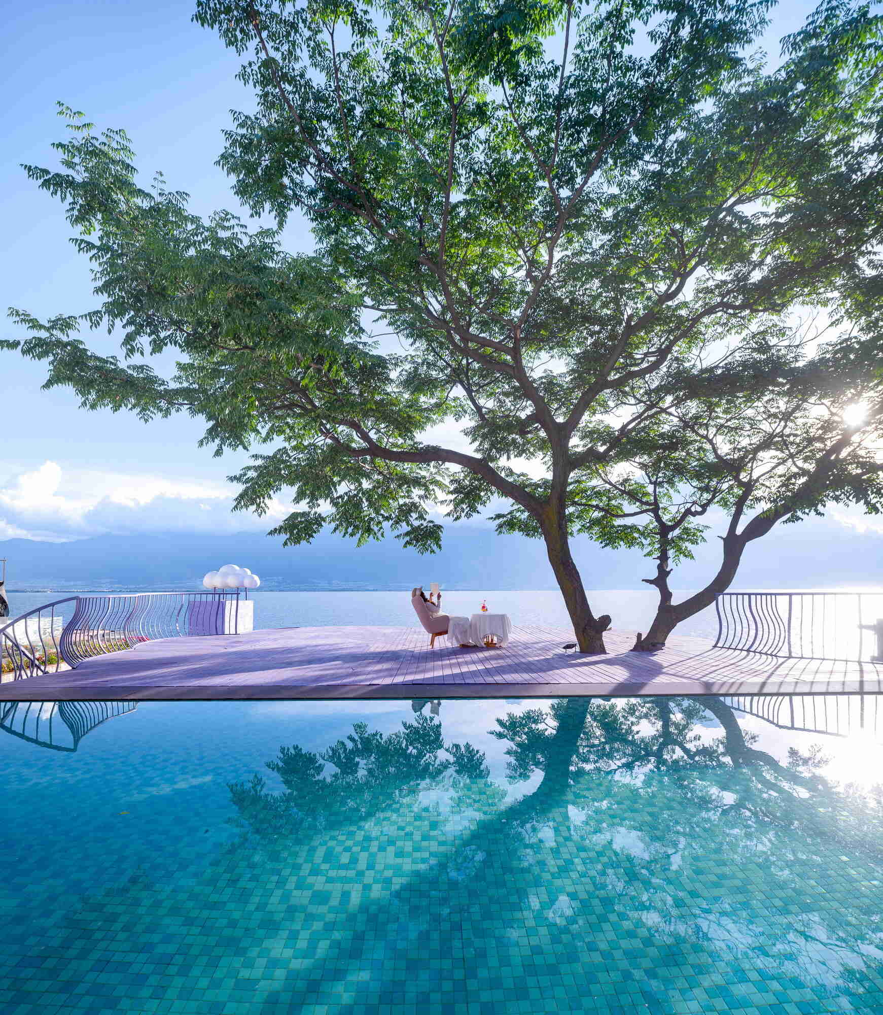 A mature tree becomes the centerpiece of the guesthouse thanks to flowing violet viewing platforms overlooking the Cangshan Mountains, Erhai Lake and the reflective pool.