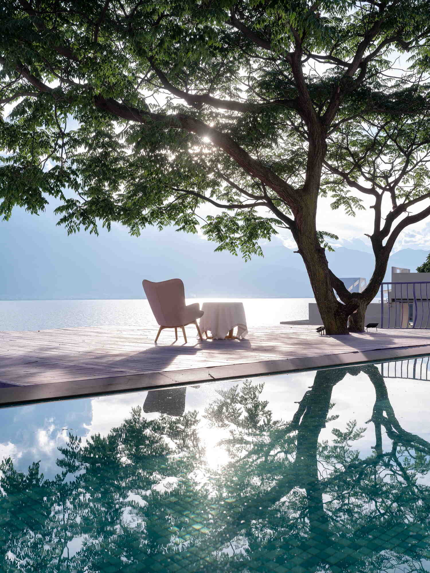 A mature tree becomes the centerpiece of the guesthouse thanks to flowing violet viewing platforms overlooking the Cangshan Mountains, Erhai Lake and the reflective pool.