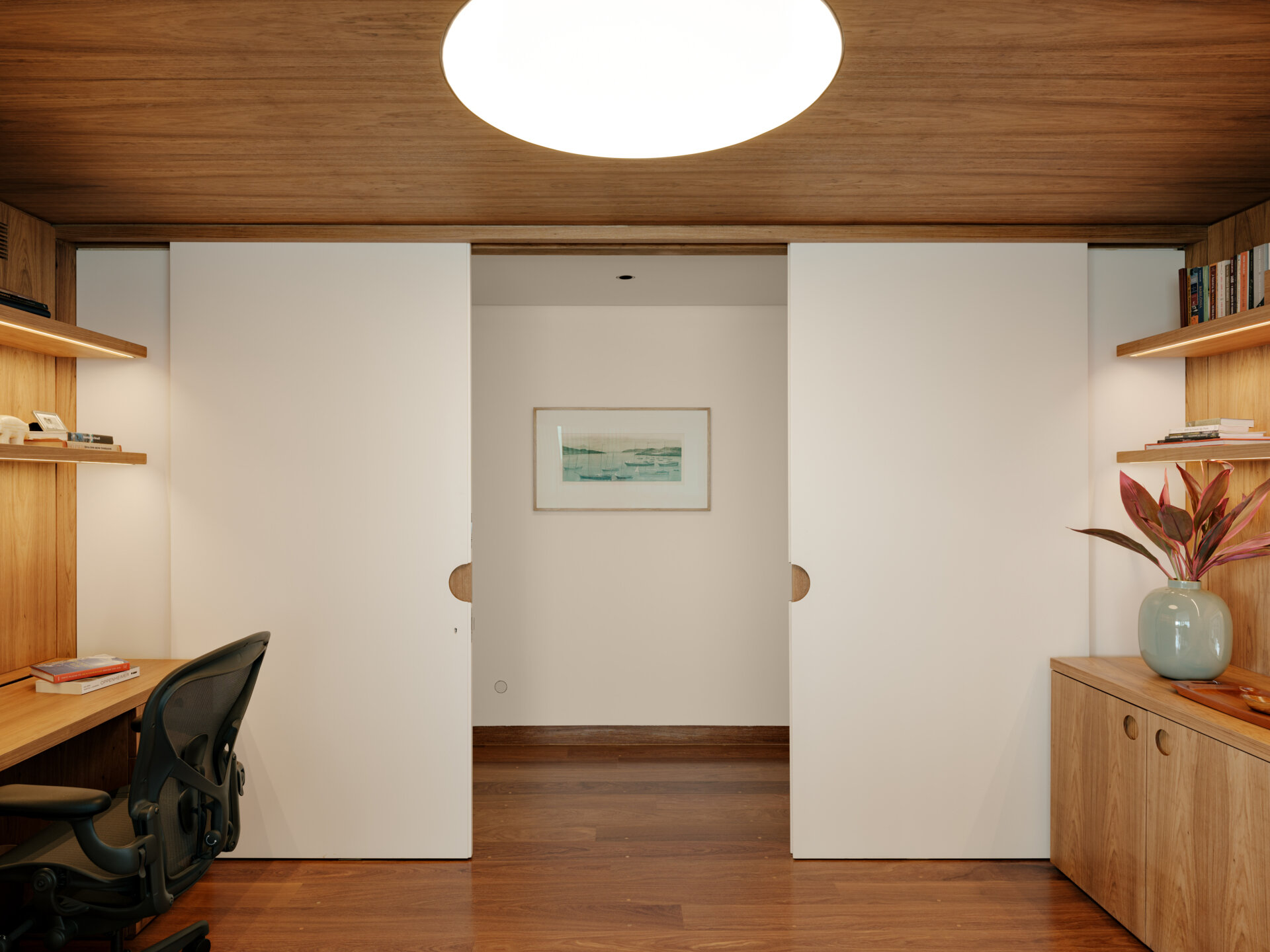 Sliding doors and timber-lined walls transform this home office into one of the apartment's most flexible spaces.