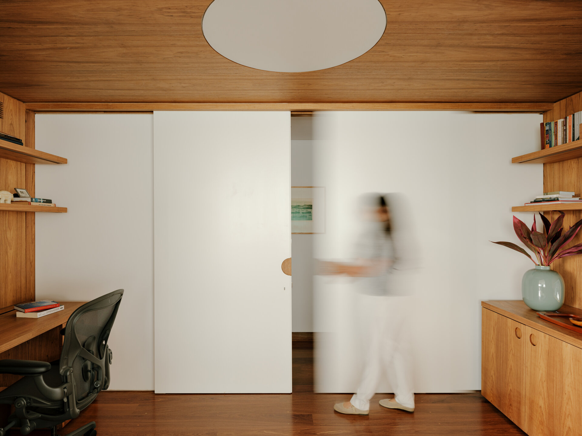 Sliding doors and timber-lined walls transform this home office into one of the apartment's most flexible spaces.