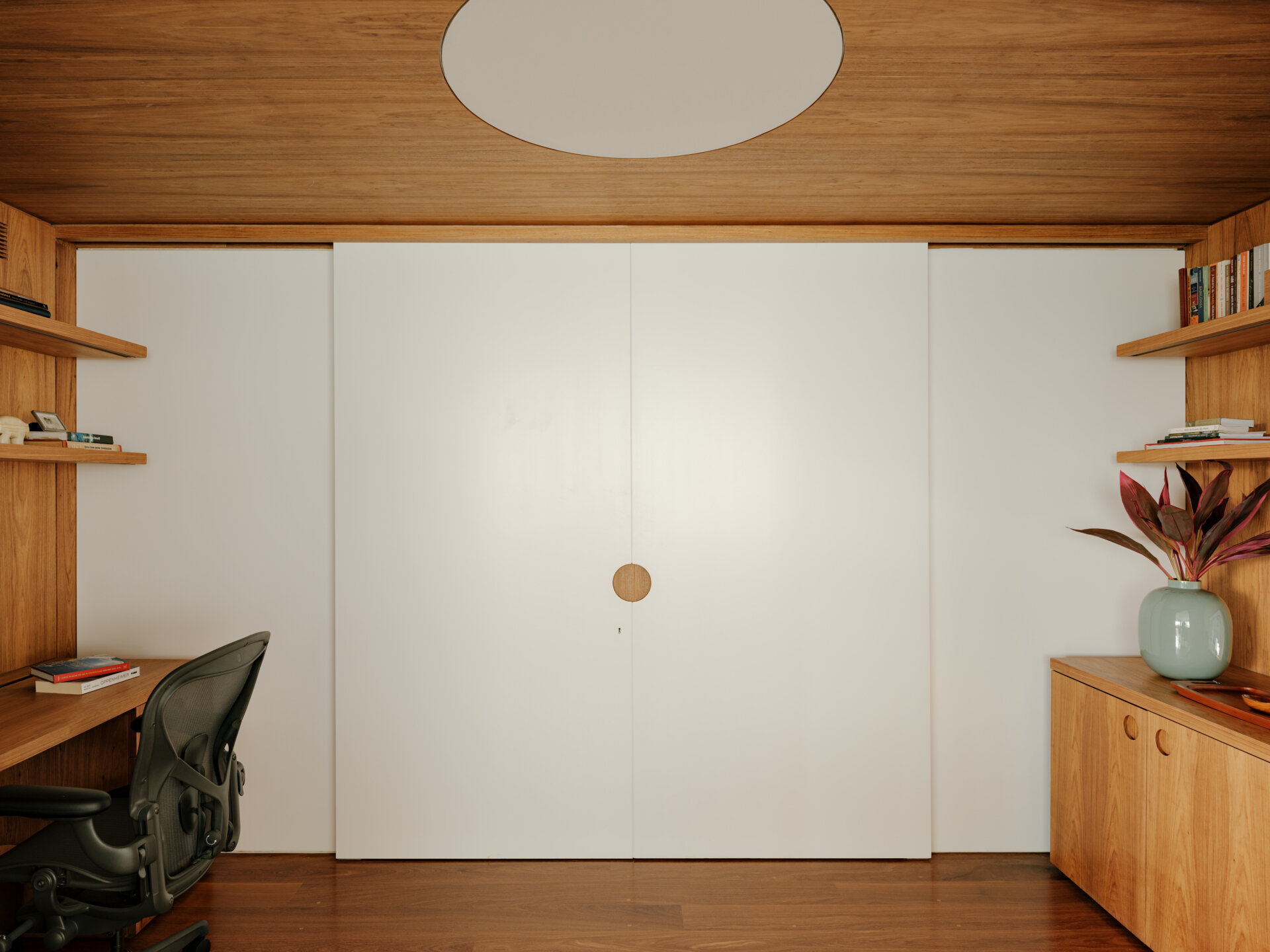 Sliding doors and timber-lined walls transform this home office into one of the apartment's most flexible spaces.
