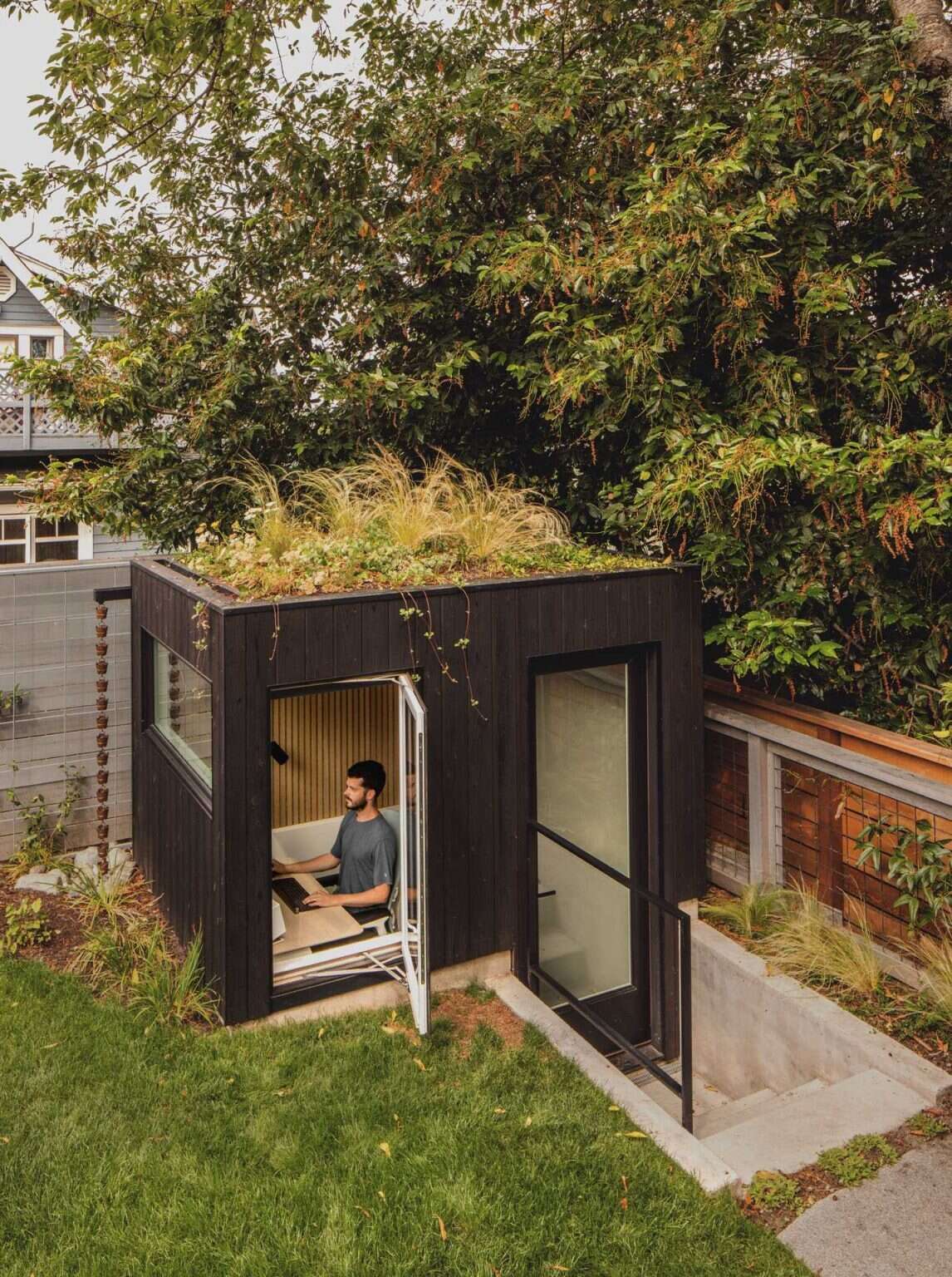This partially sunken backyard office features a green roof and peaceful garden views, creating an inspiring place to work from home.