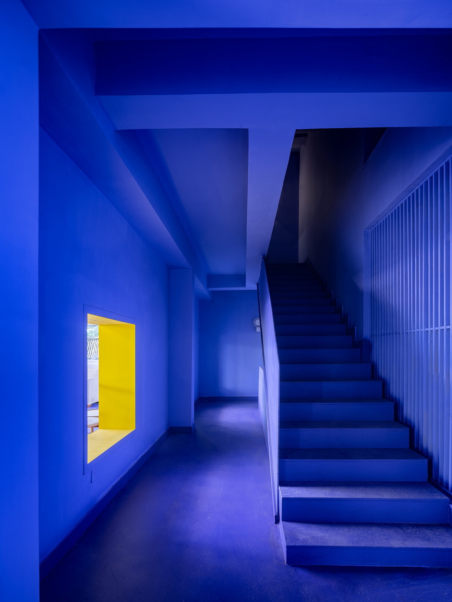 A dramatic violet tunnel and bright yellow viewing window transform a simple staircase into one of the guesthouse's most memorable architectural moments.