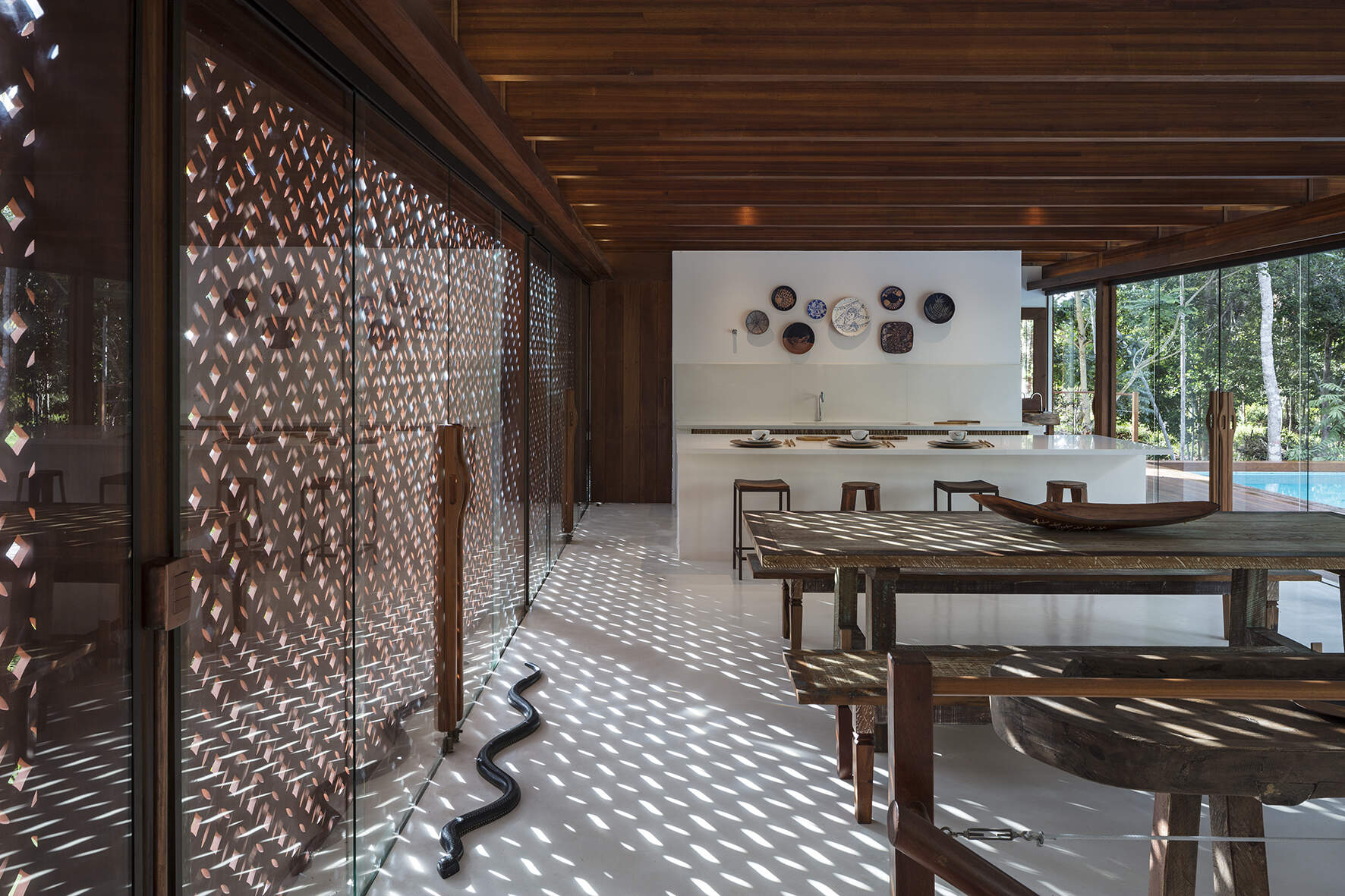 Inside, a 78 foot (24-metre) open-plan living space combines custom furniture, artisan lighting and seamless white cement floors beneath exposed timber beams.